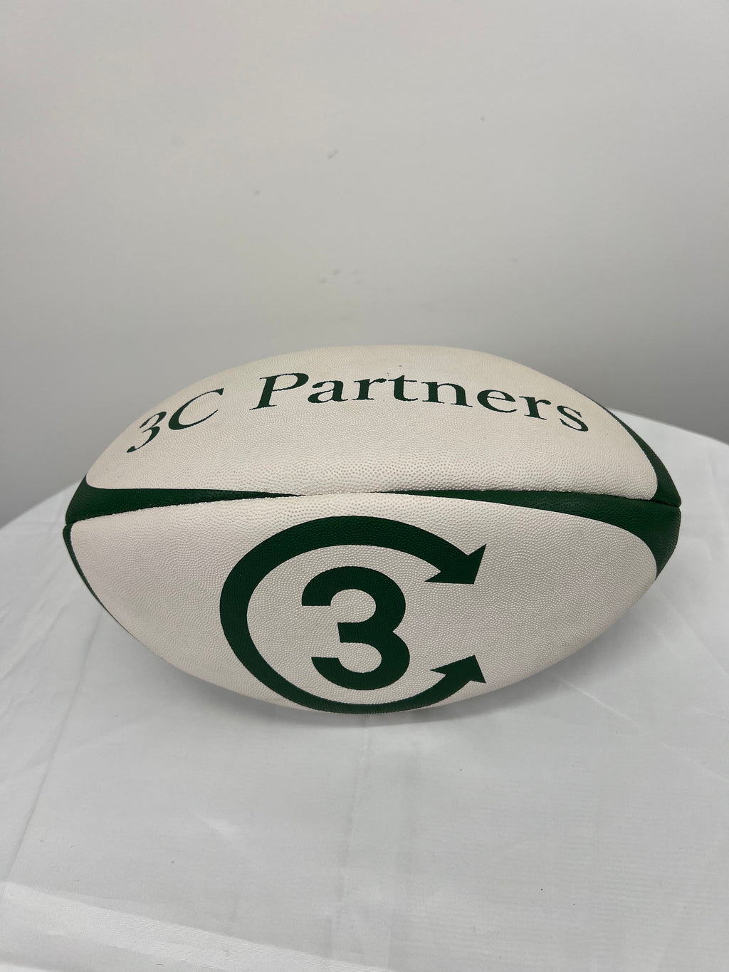 White and green rugby ball with 3C Partners branding on white table