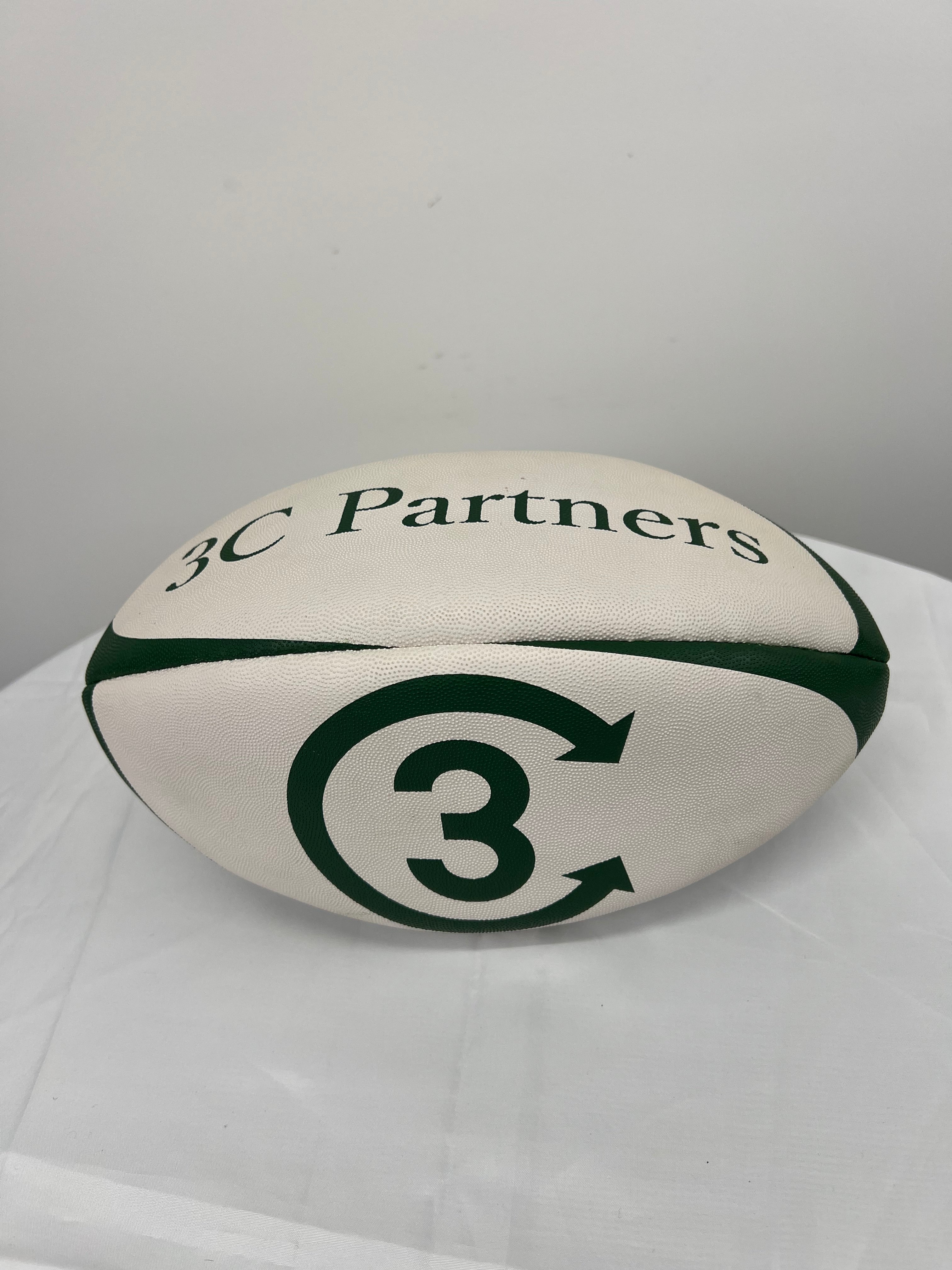 White and green rugby ball with 3C Partners branding on white table