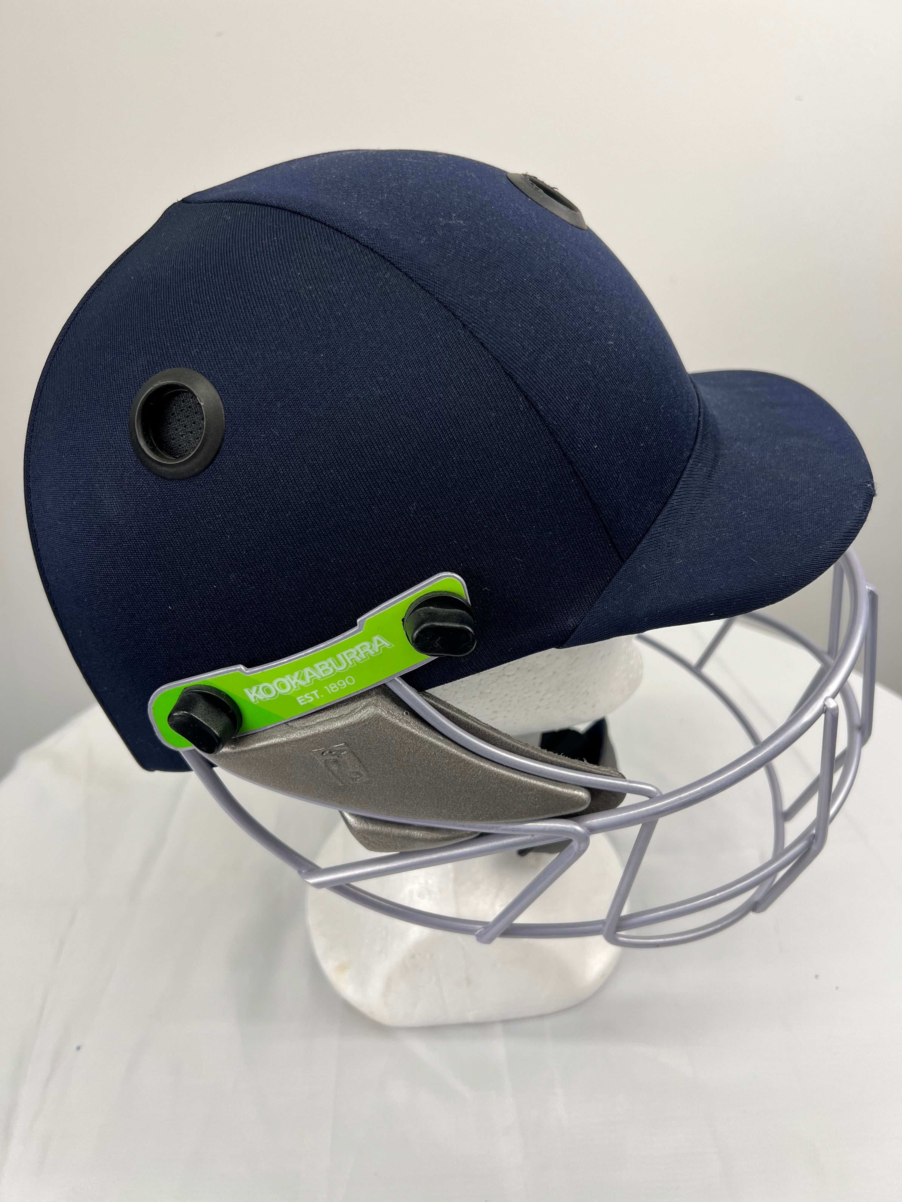 Side view of navy blue youth cricket helmet showing ventilation and adjustable straps with Kookaburra branding
