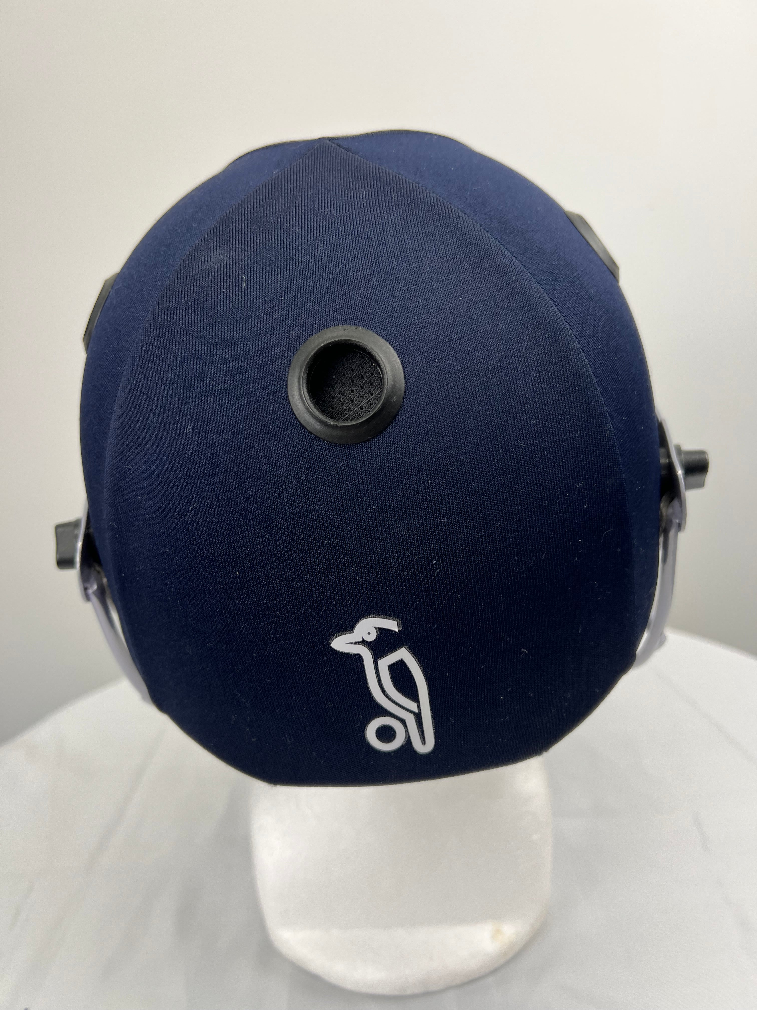 Top view of navy blue cricket helmet displaying ventilation hole and Kookaburra logo