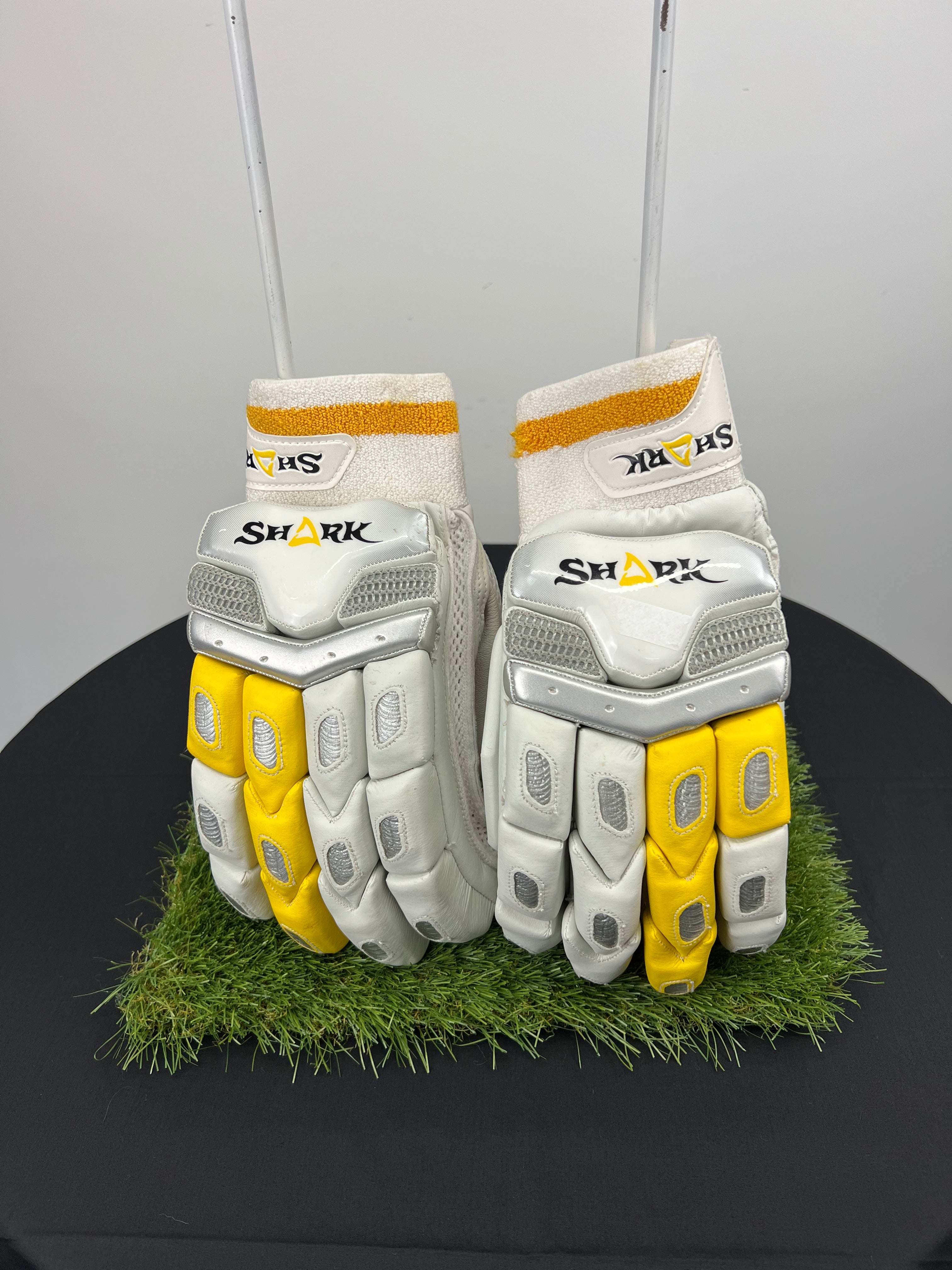 Front view of Shark left hand cricket batting gloves showing white and yellow padded protection with brand logo