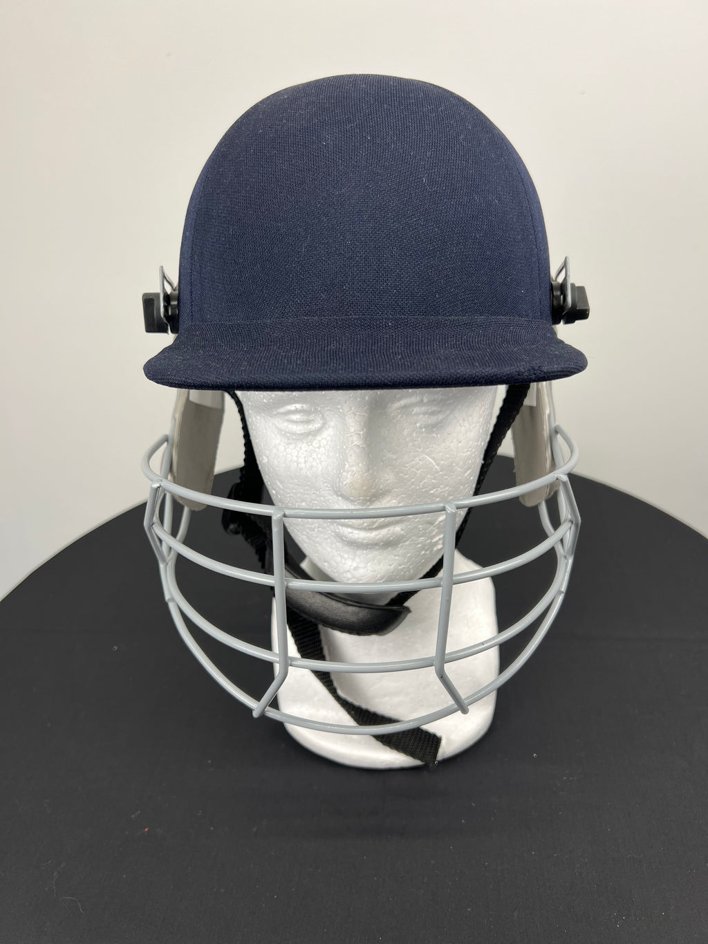 Front view of navy Slazenger youth cricket helmet with grey face guard displayed on mannequin head
