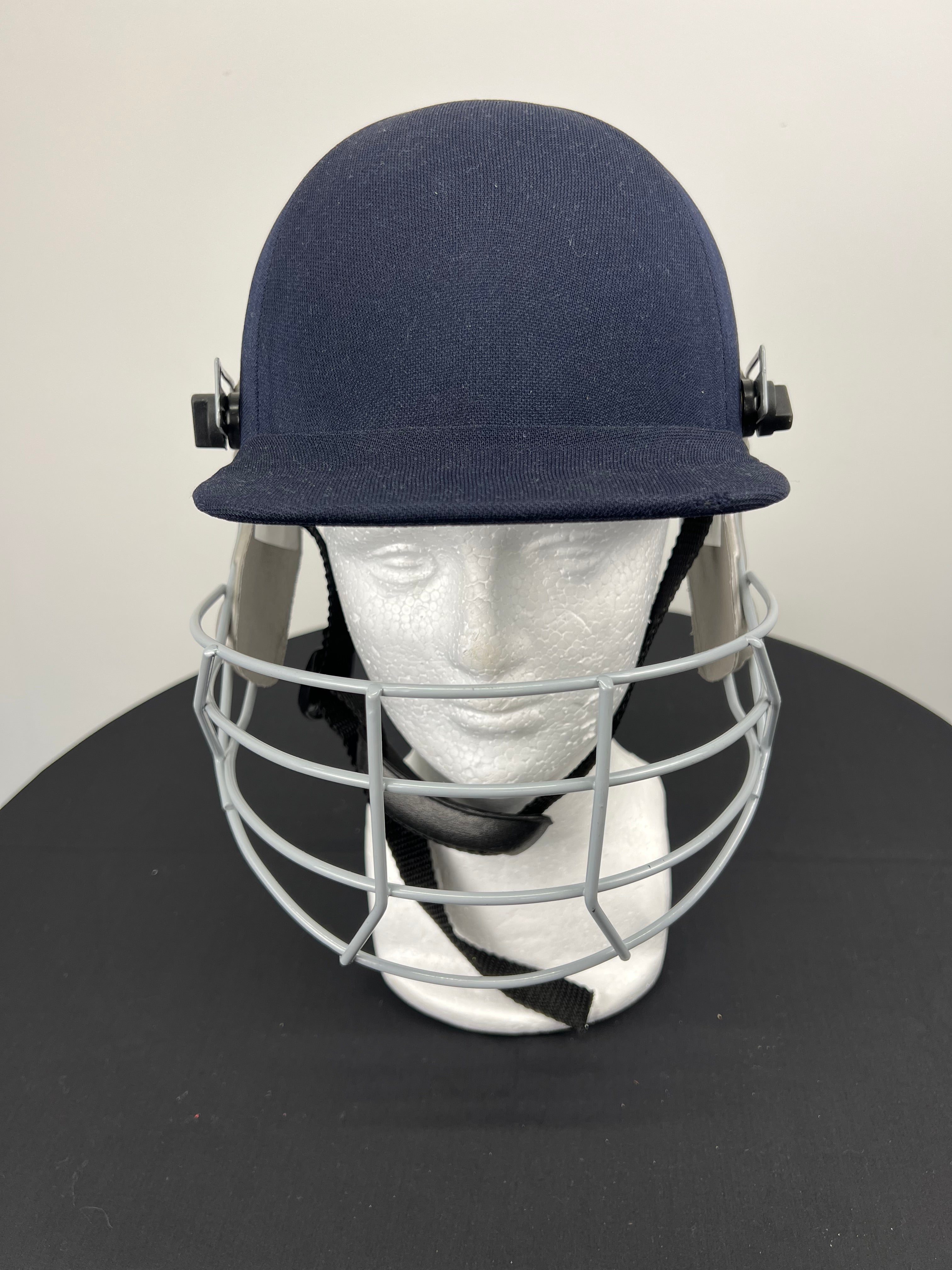 Front view of navy Slazenger youth cricket helmet with grey face guard displayed on mannequin head