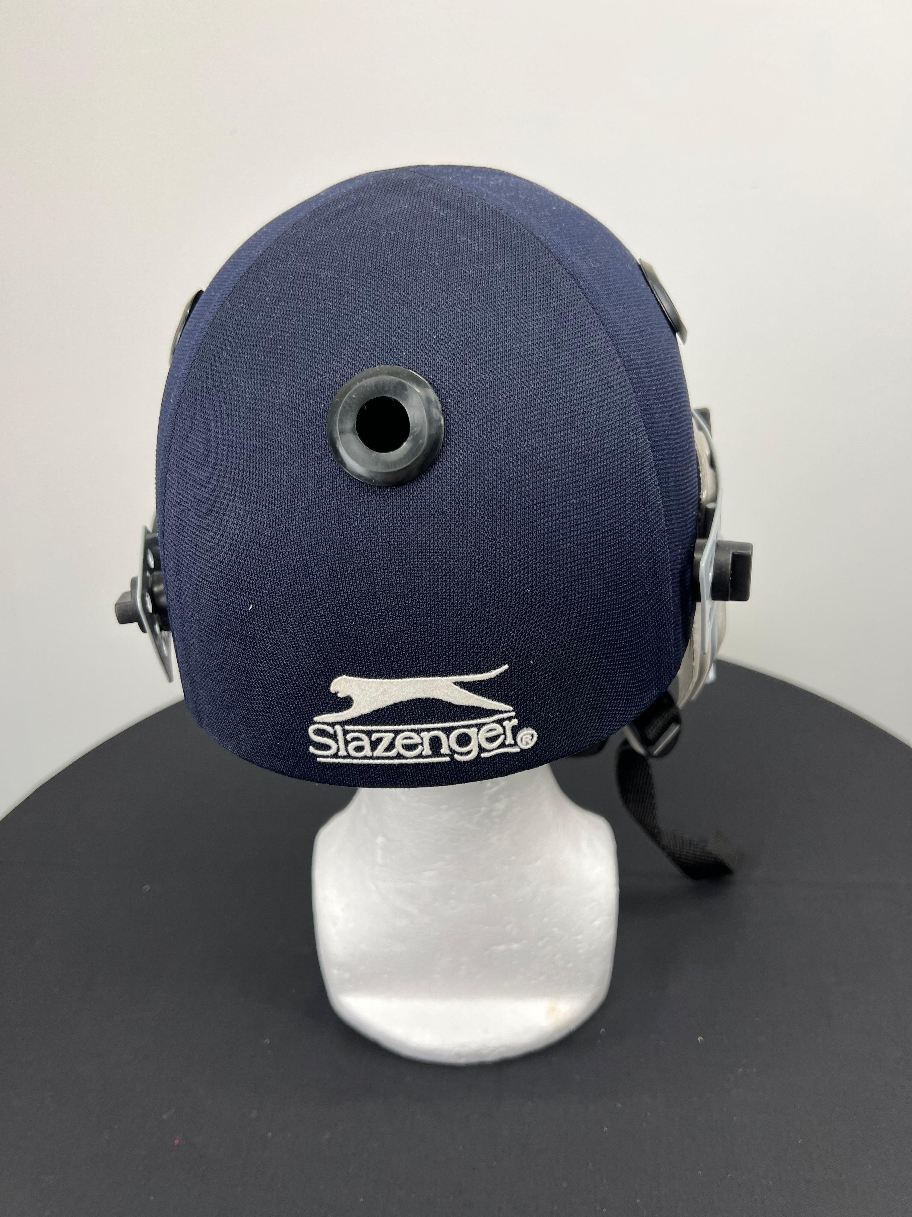 Back view of navy Slazenger cricket helmet highlighting brand logo embroidered on fabric surface
