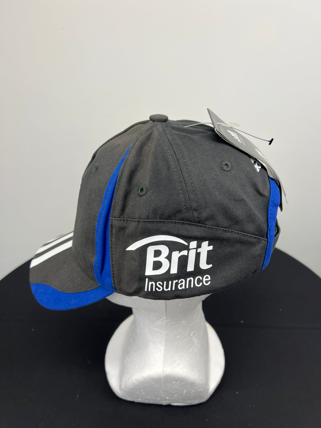 Side view of black and blue baseball cap showing Brit Insurance logo and blue piping