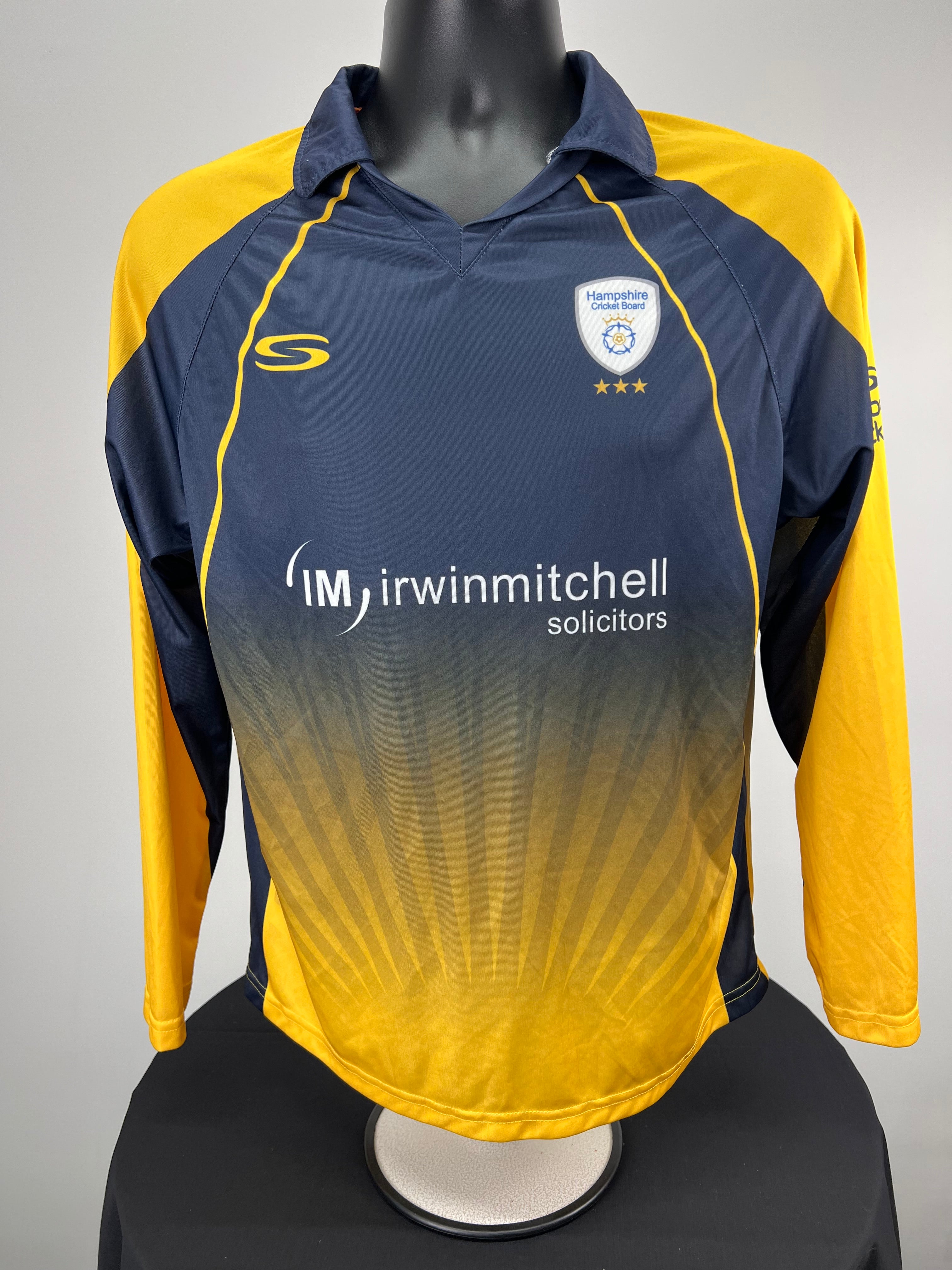 Front view of Hampshire Cricket Board long sleeve cricket top in navy and yellow with sponsor logos