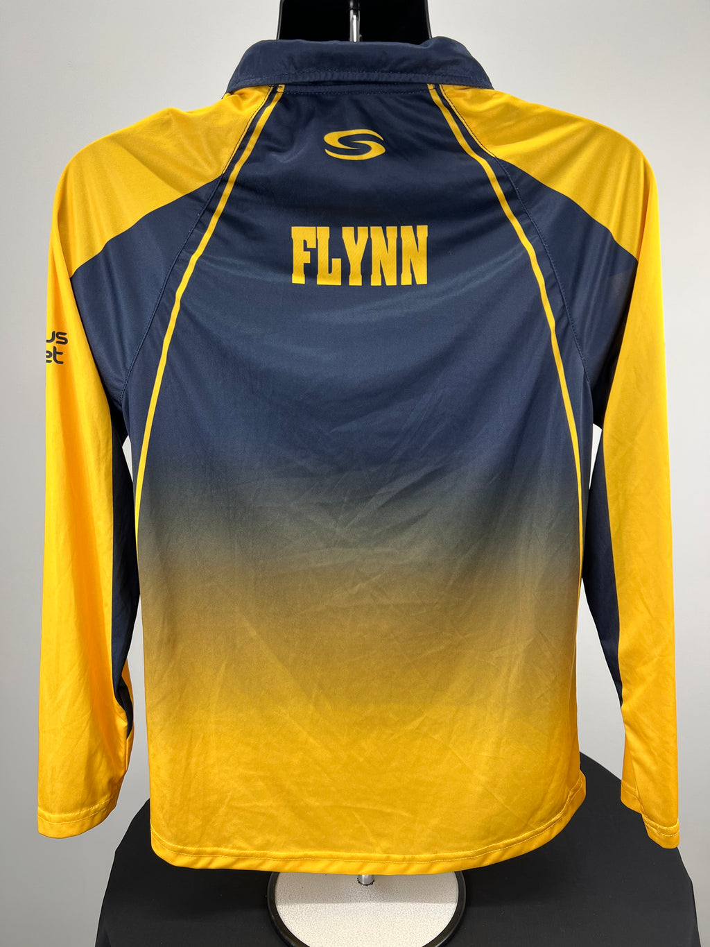 Back view of Hampshire Cricket Board cricket top showing yellow 'FLYNN' name print on navy and yellow background