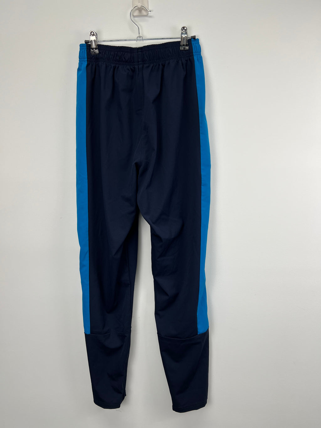 Back view of Men’s New Balance cricket tracksuit trousers showing elasticated waistband and blue side stripes