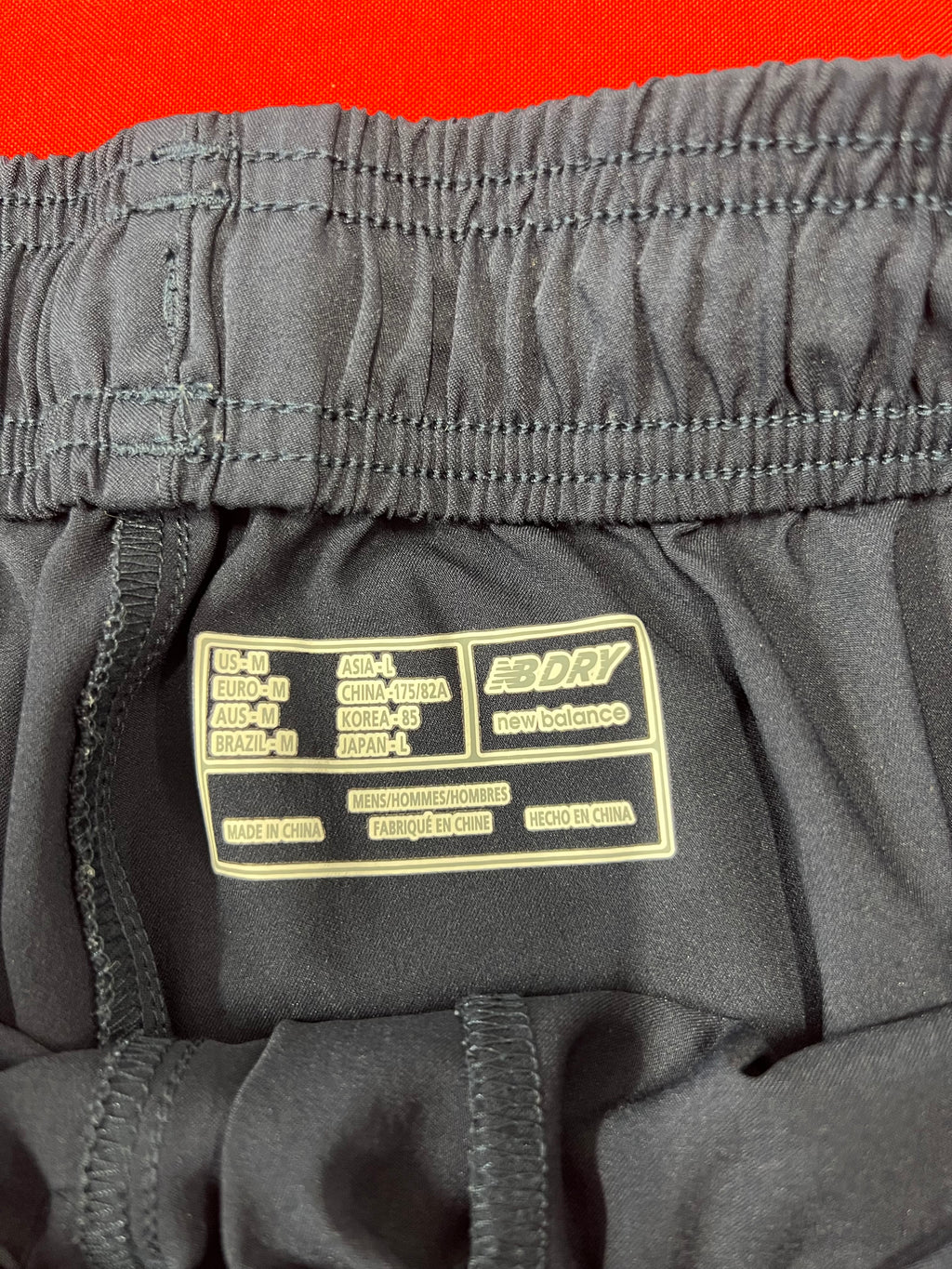 Close-up of inner label displaying size medium and NB Dry technology of New Balance cricket tracksuit trousers