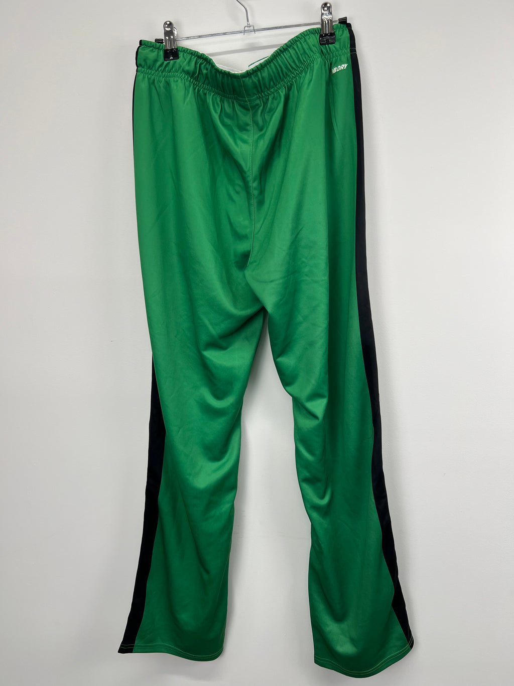back view of women's green New Balance tracksuit bottoms displaying smooth fabric and black side panels
