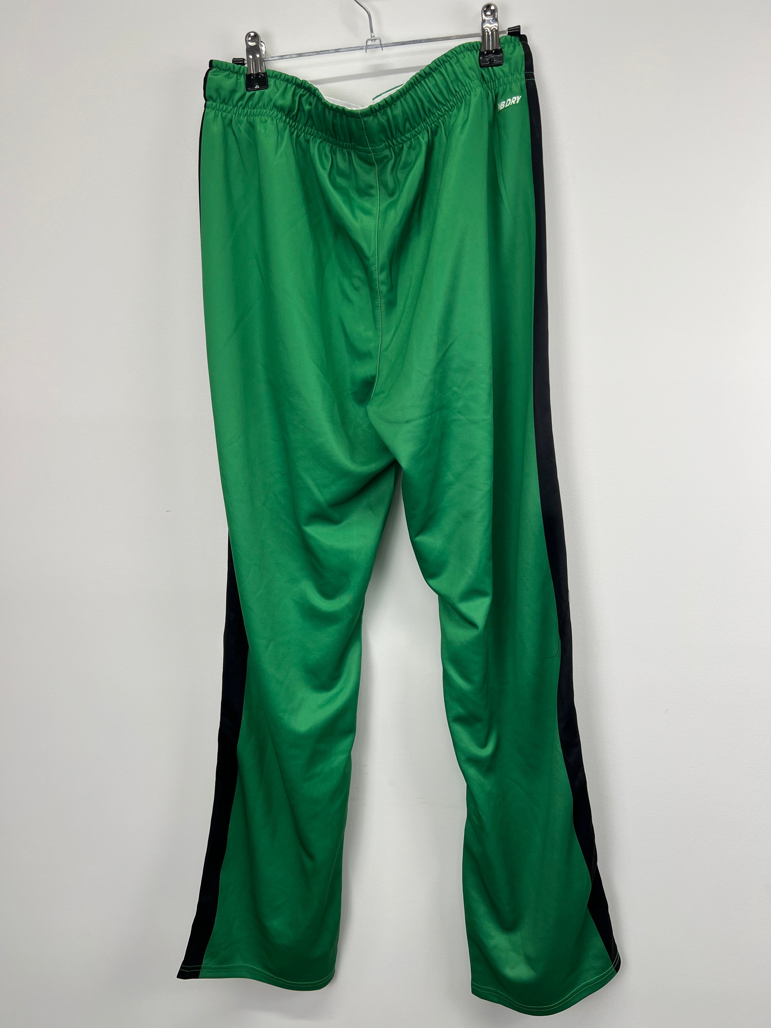 back view of women's green New Balance tracksuit bottoms displaying smooth fabric and black side panels
