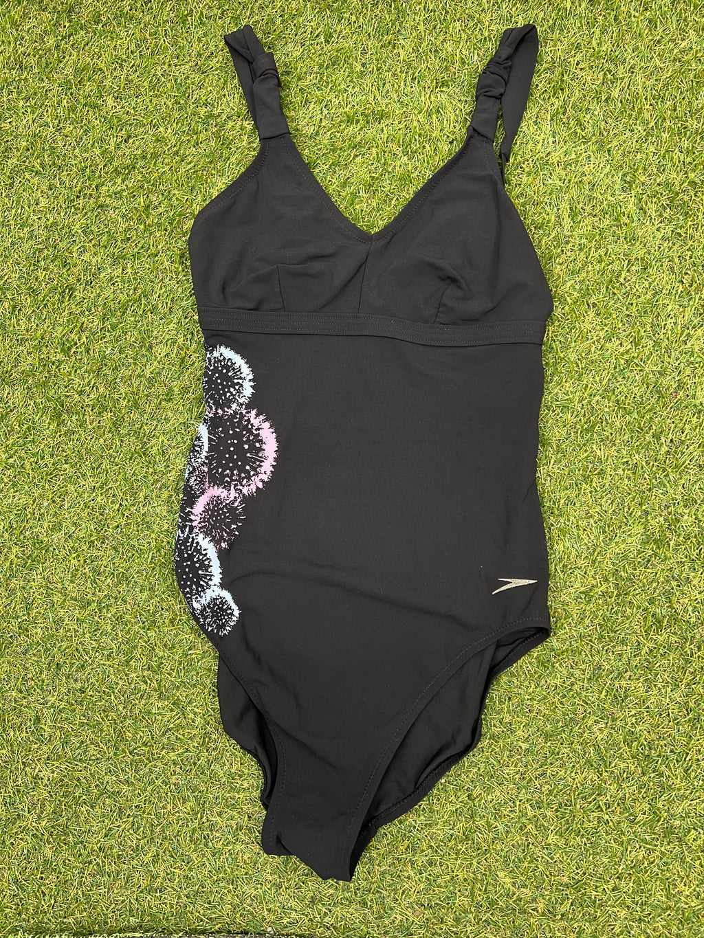 Speedo Sculpture black swimsuit laid flat on green grass showing front view with decorative print on side