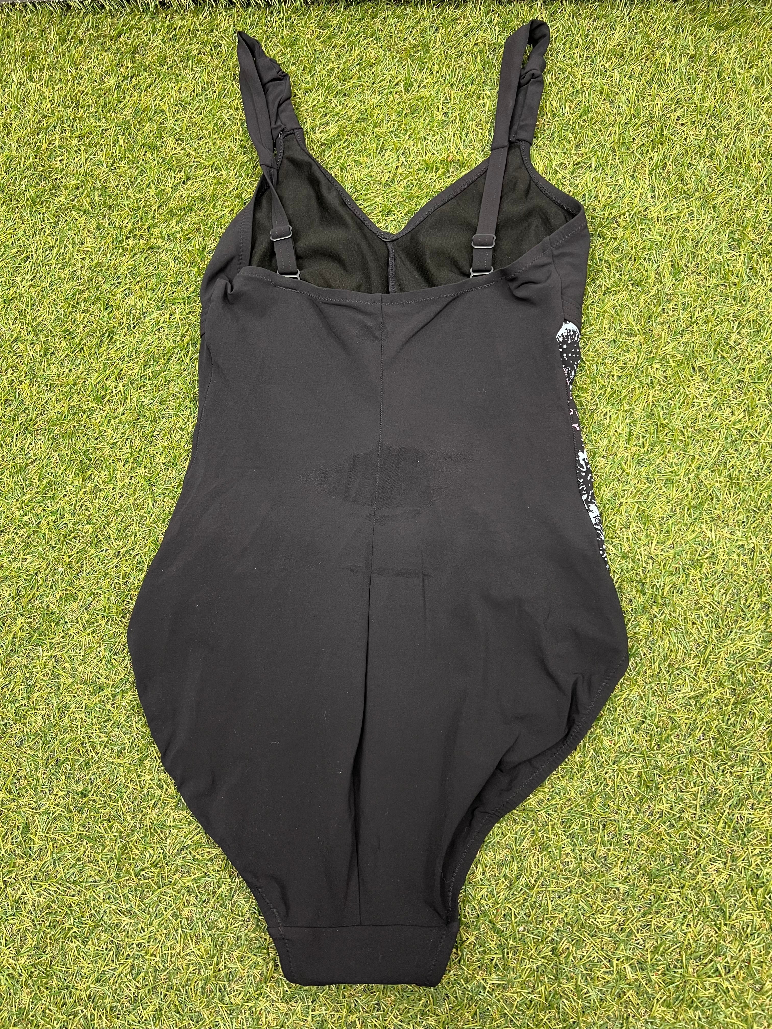 Speedo Sculpture black swimsuit laid flat on grass showing back view with adjustable straps