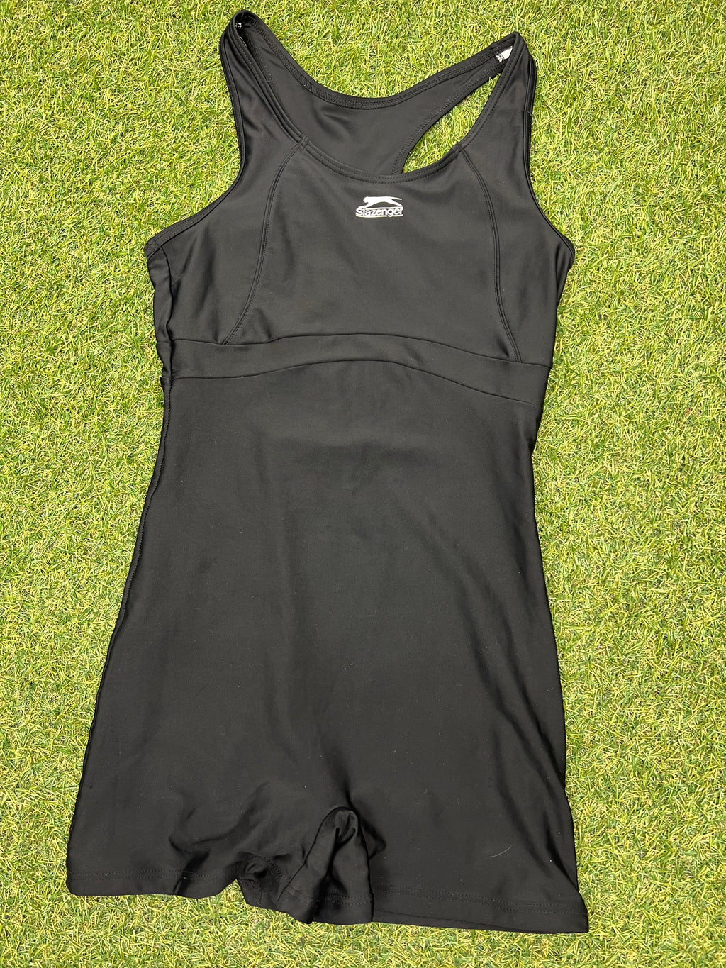 Front view of black Slazenger swimsuit size 10 lying flat on grass