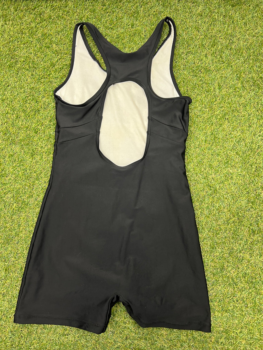 Back view of black Slazenger swimsuit showing racerback with keyhole cutout on grass