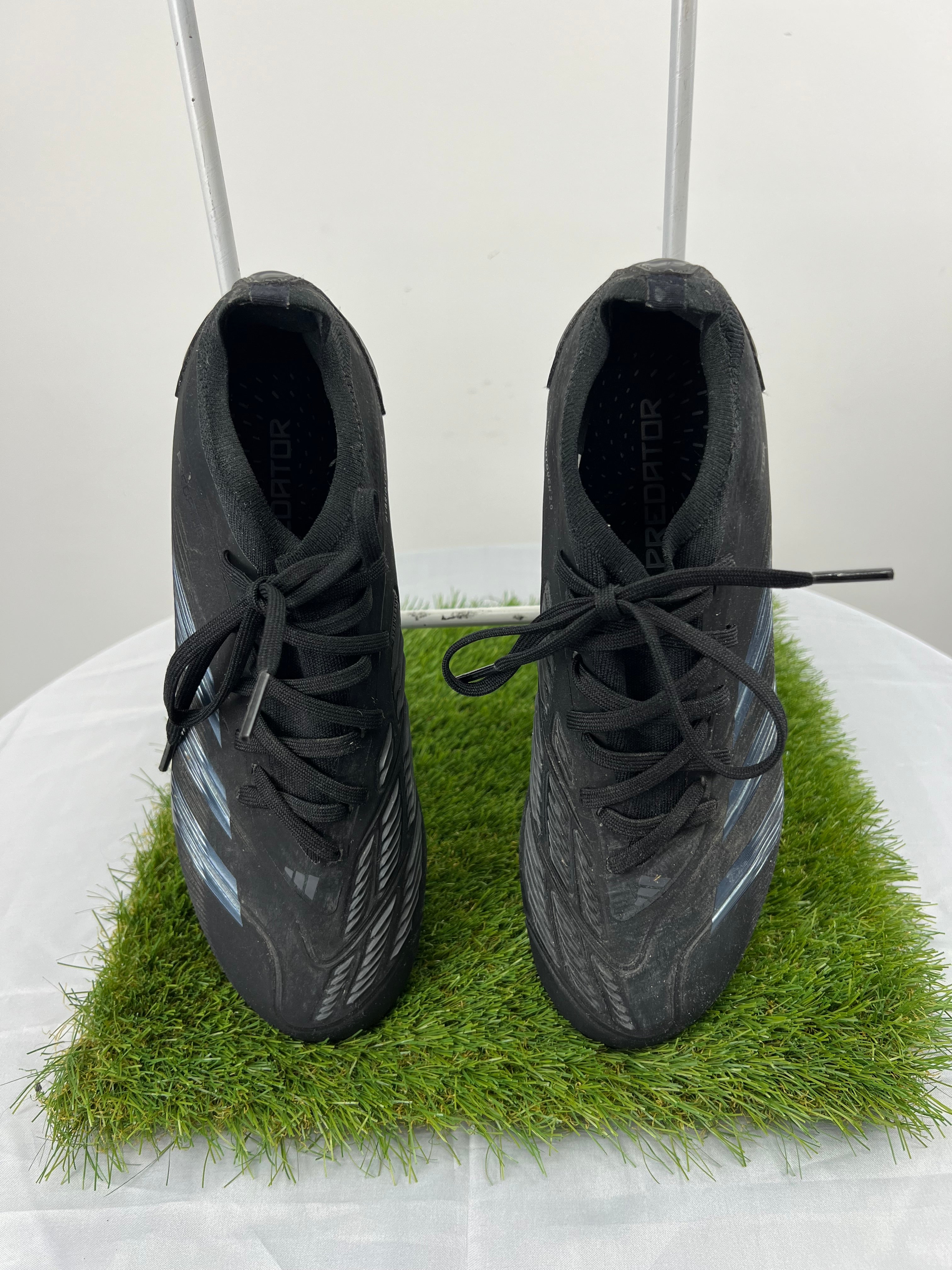 Top view of Adidas Predator football boots in black with laces tied on artificial grass