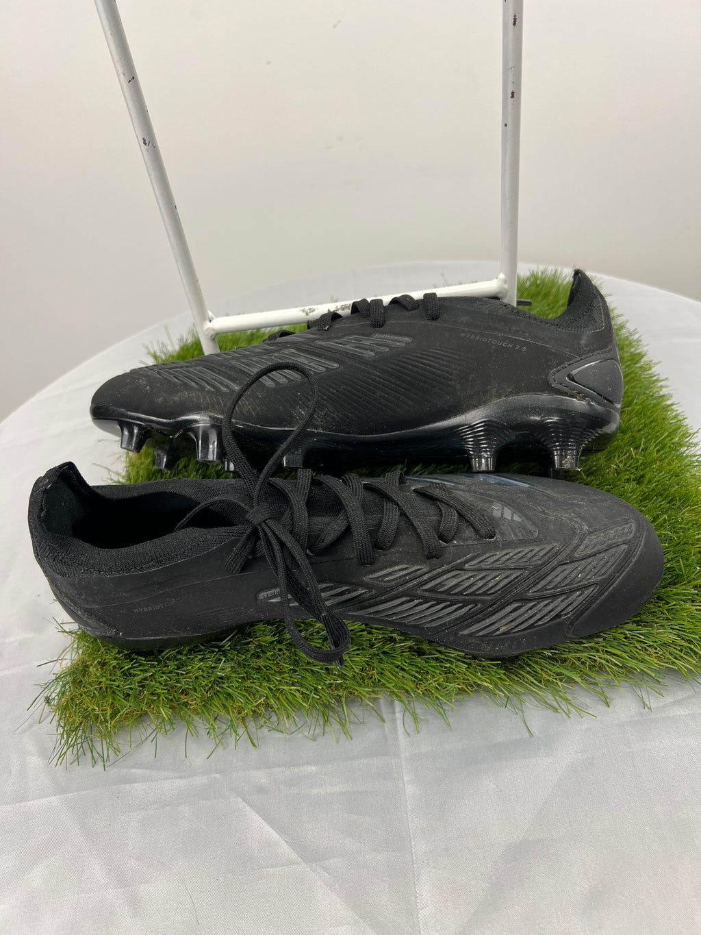 Side view of Adidas Predator football boots showing streamlined black design with grey accents