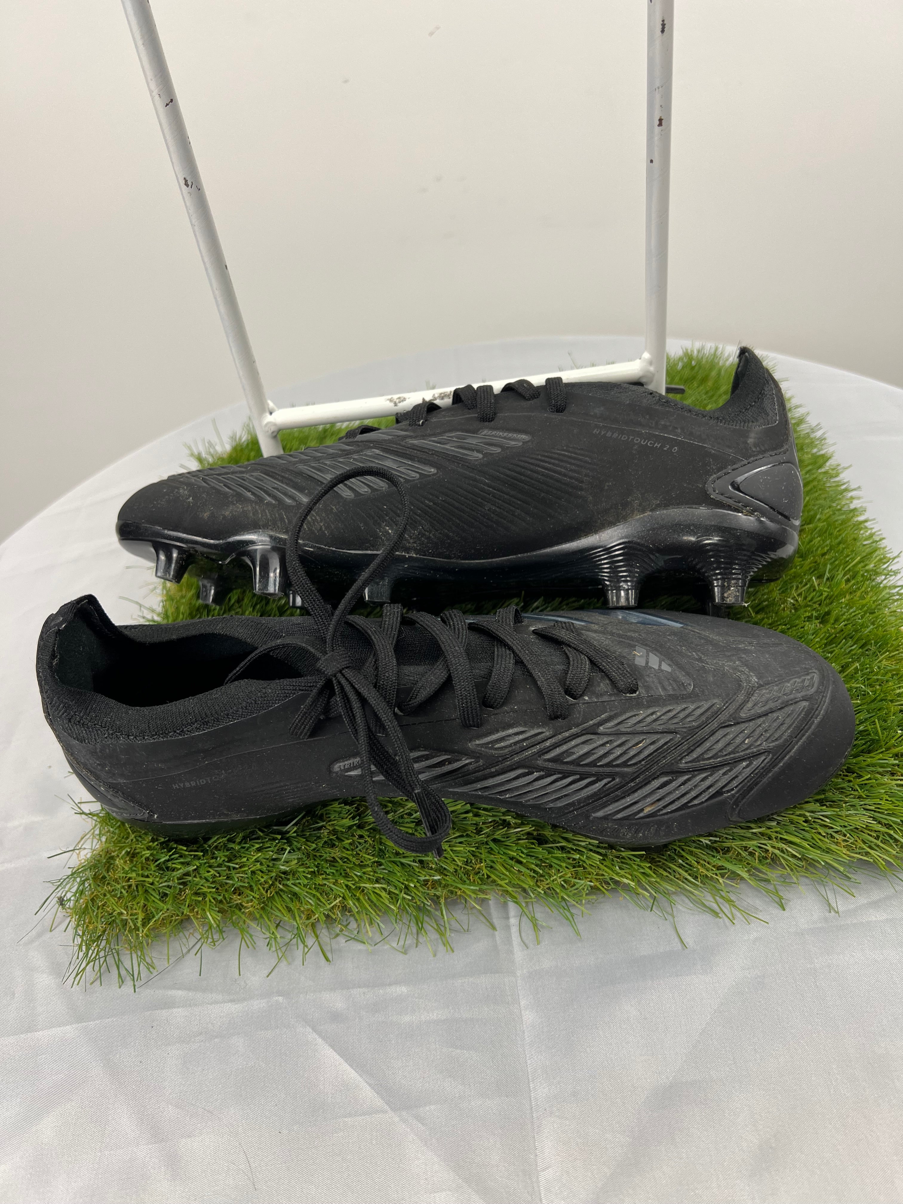 Side view of Adidas Predator football boots showing streamlined black design with grey accents
