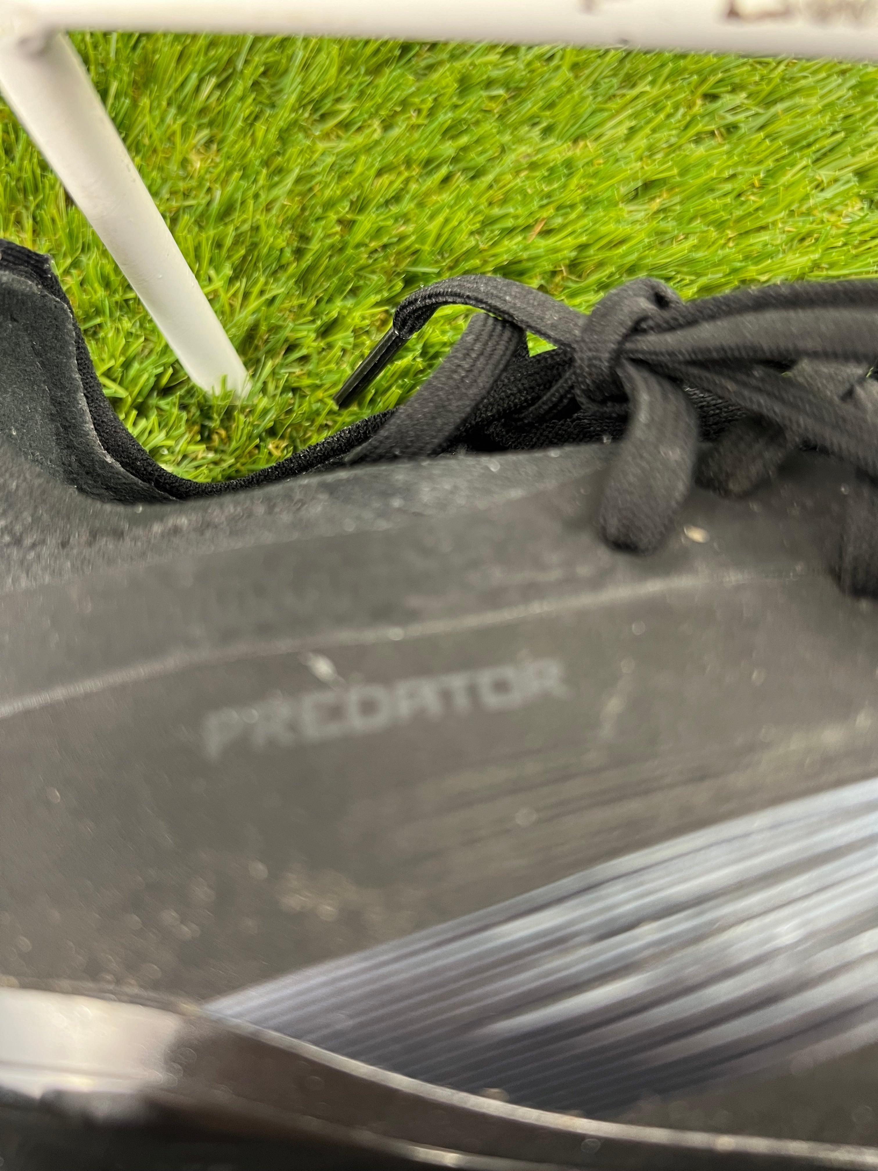 Close-up of Adidas Predator branding on the synthetic upper material of the boots