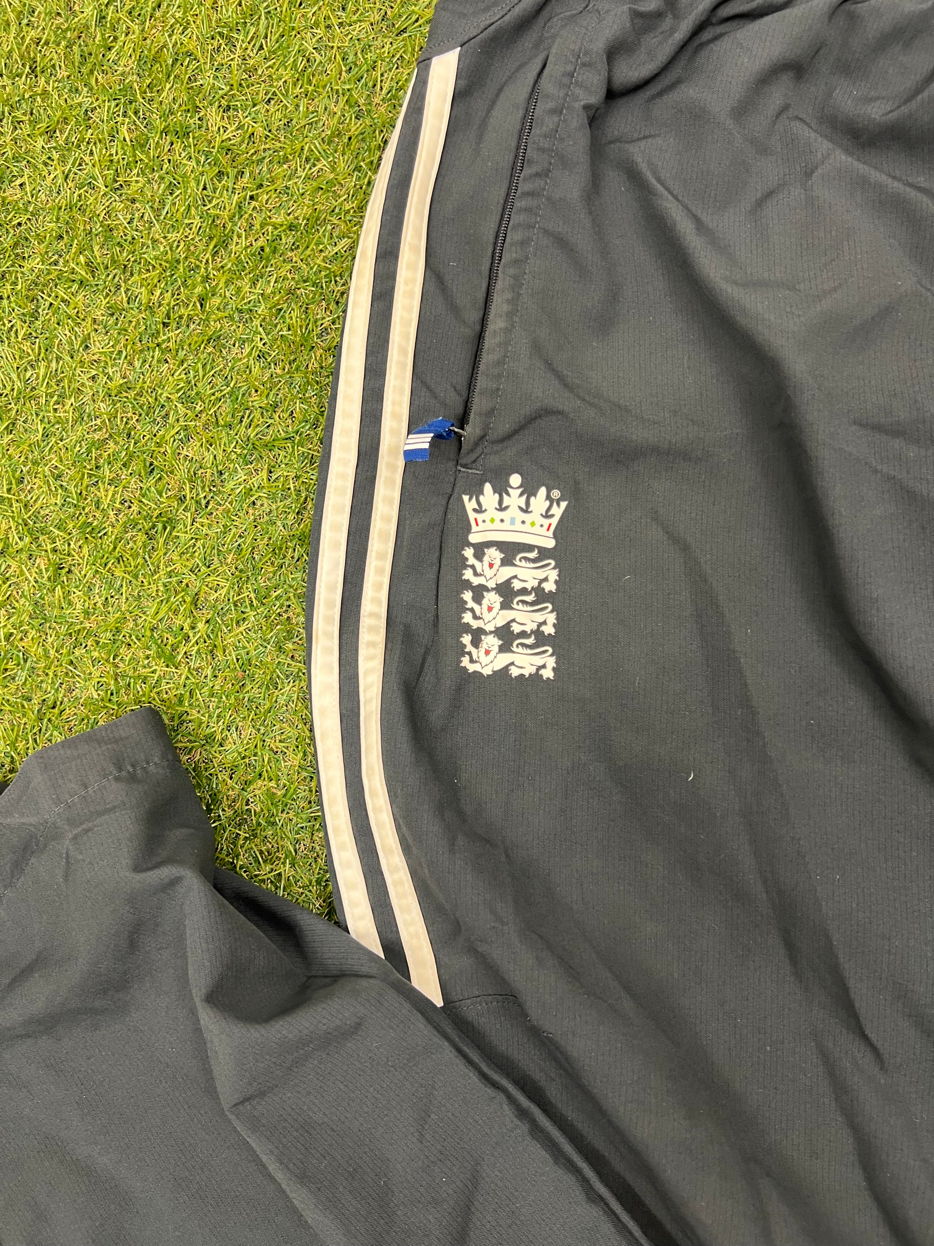 Close-up of left front pocket with England cricket logo and zipper detail on black trousers