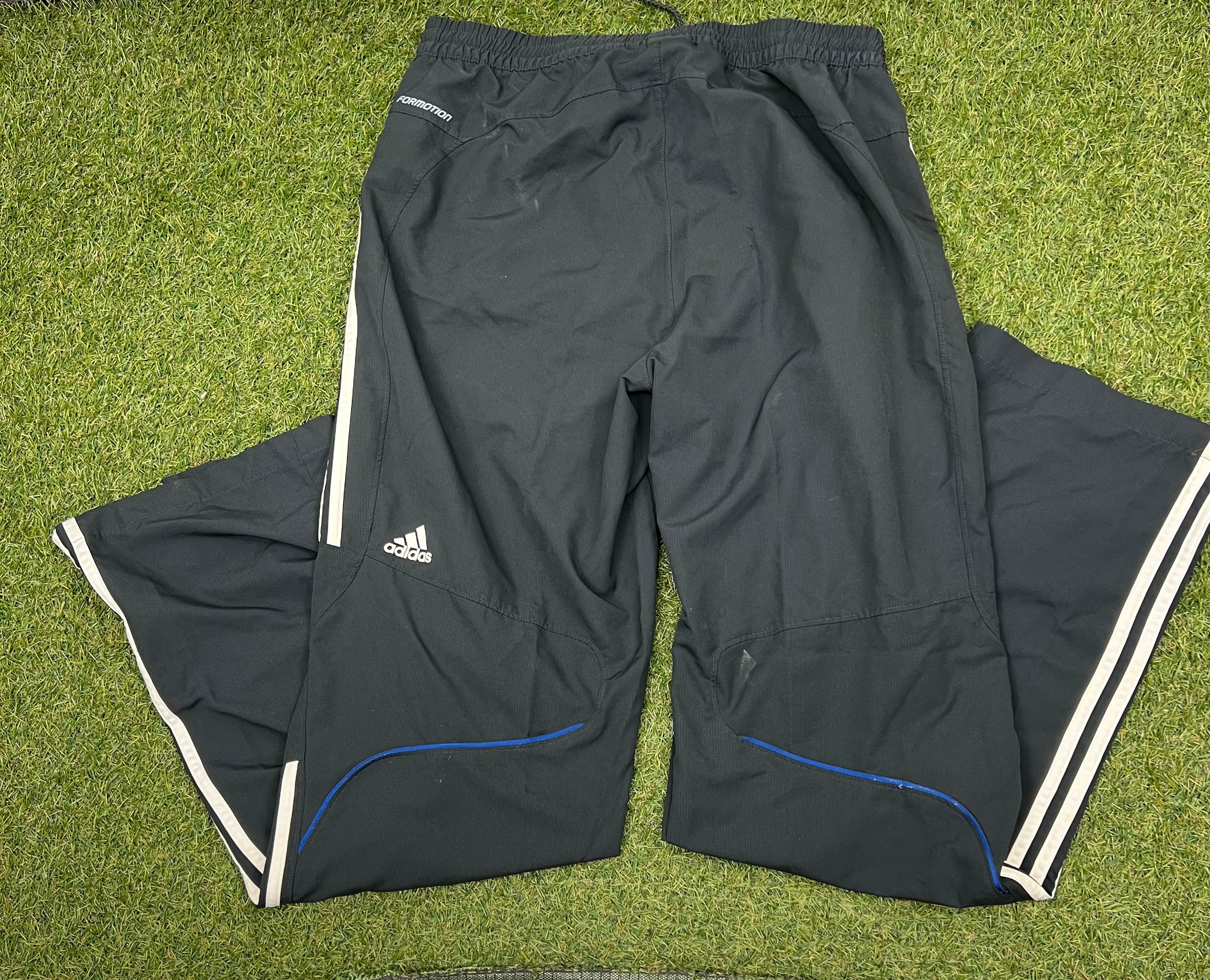 Back view of black tracksuit trousers showing adidas logo and white stripes on legs