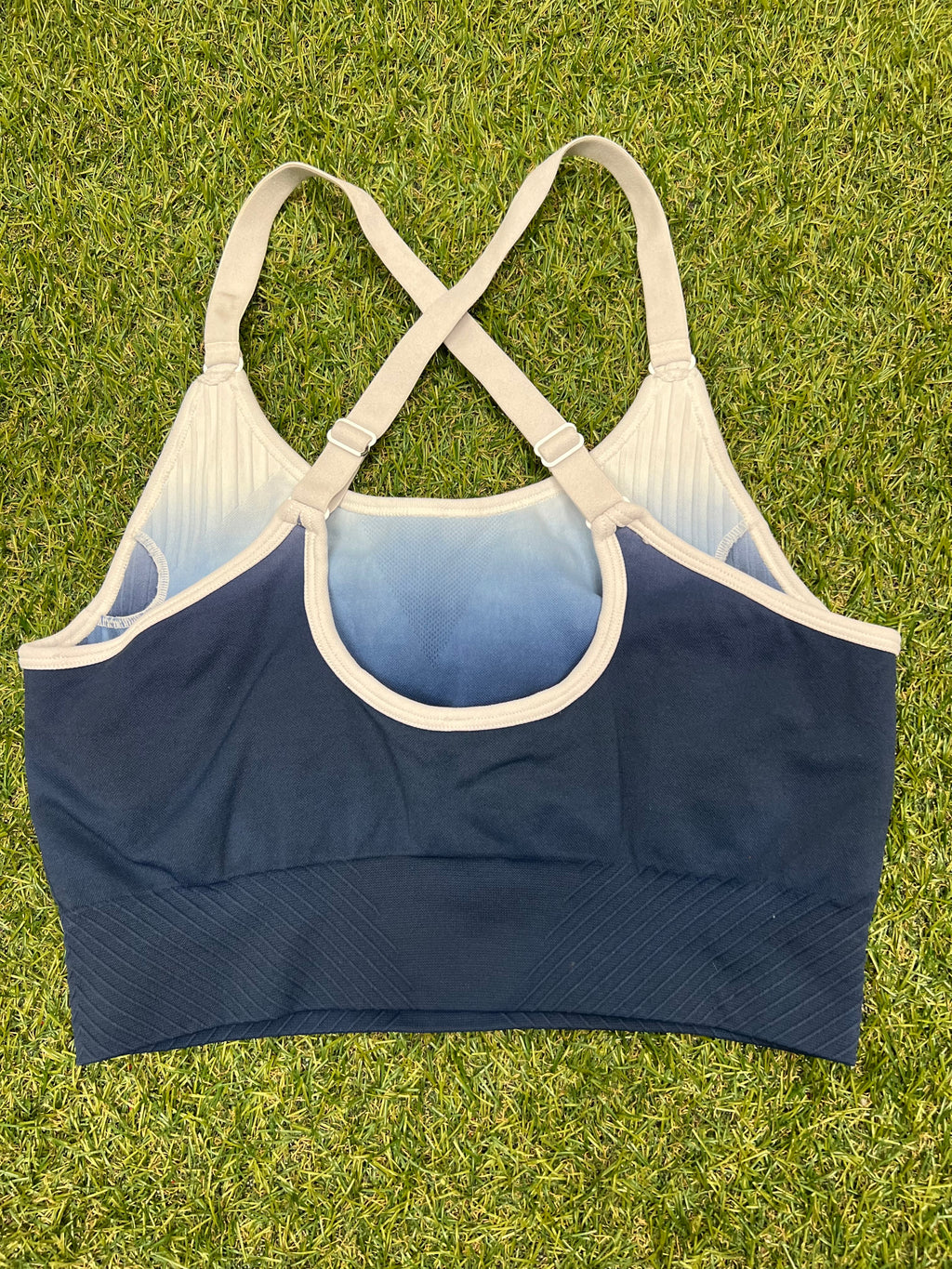 Back view of USA Pro sports bra top showing cross-back adjustable straps on grass