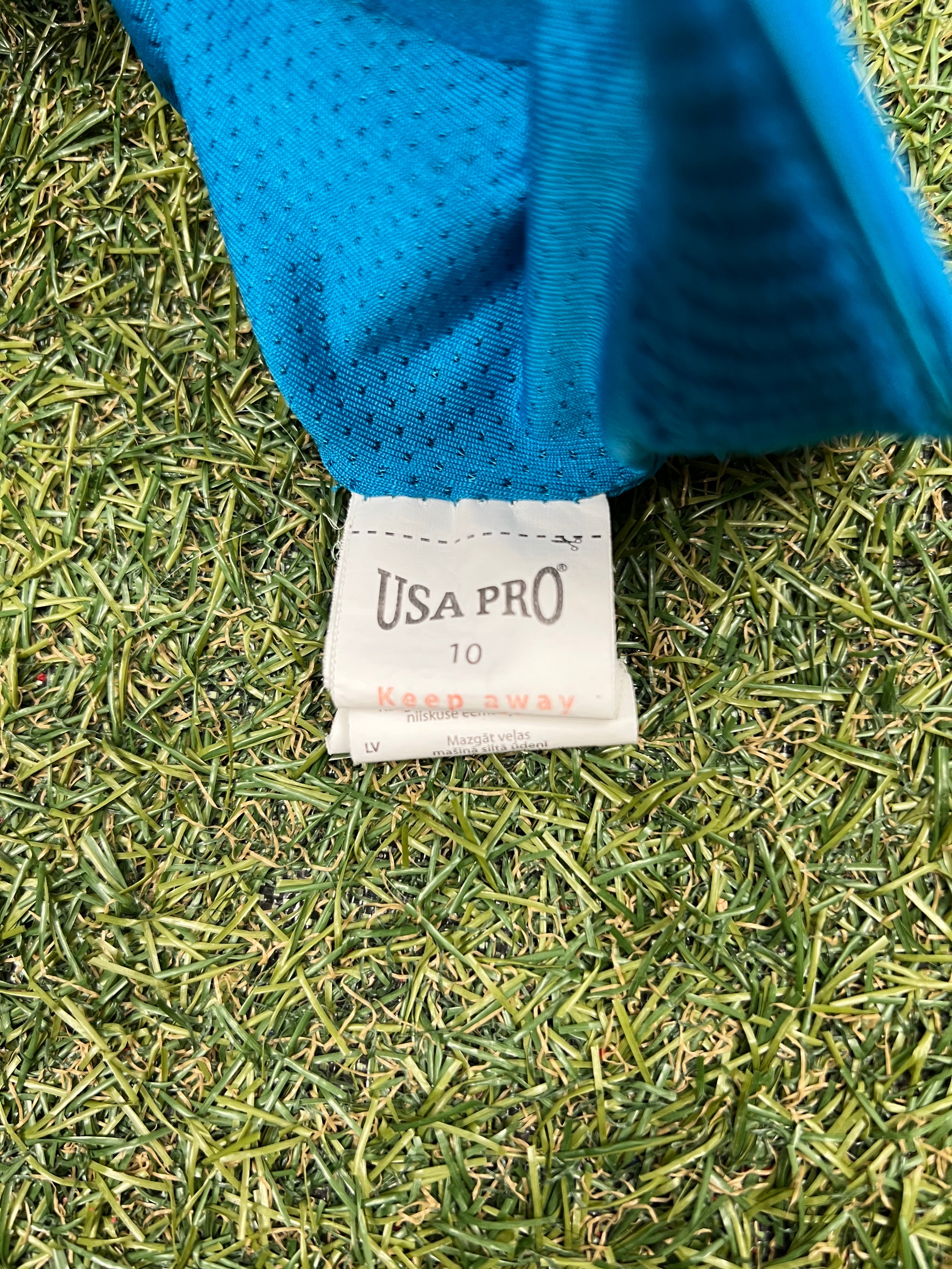 Close-up of size label inside USA Pro turquoise sports bra on grass