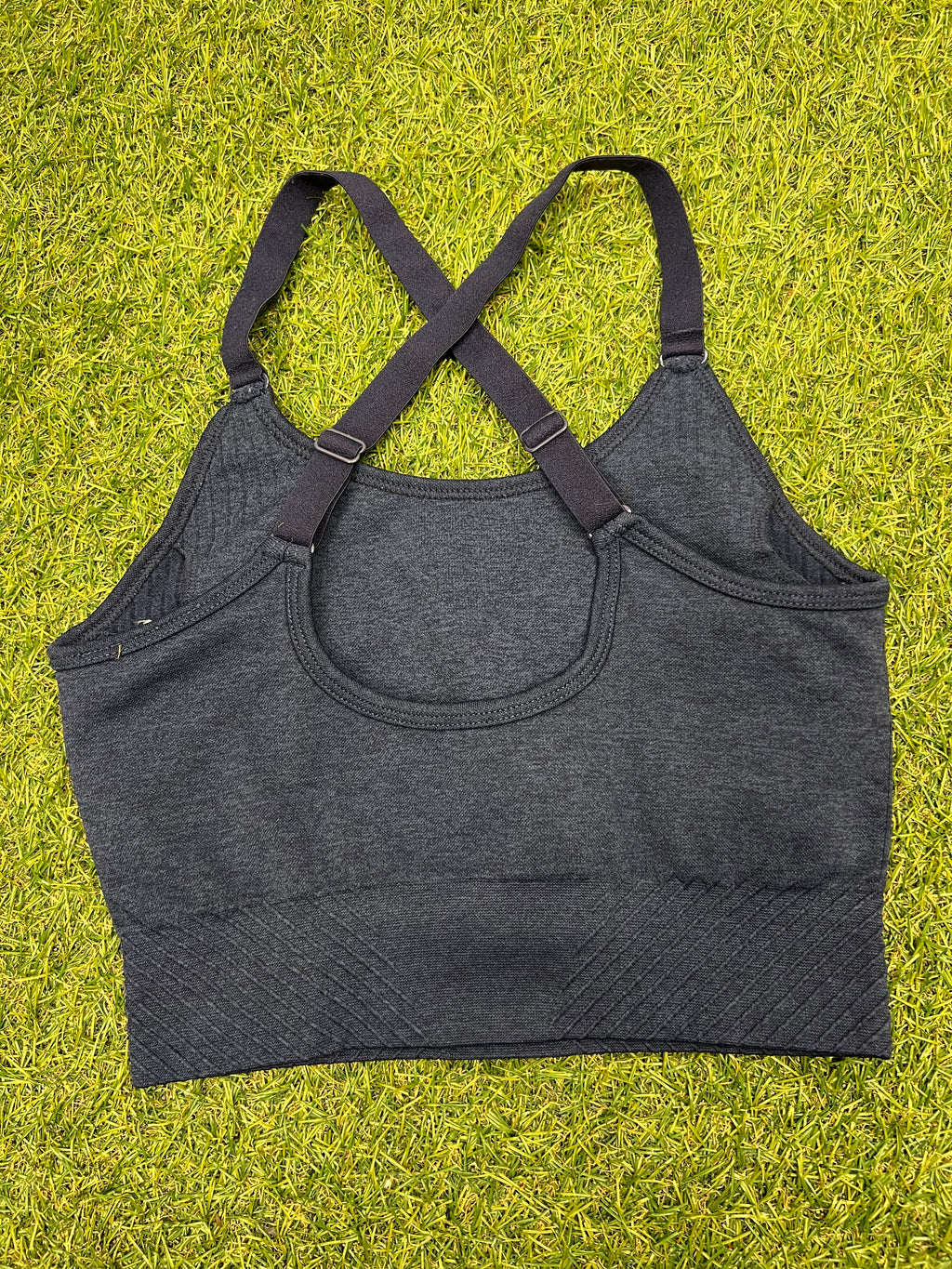 Back view of USA Pro navy marl sports bra top showing adjustable criss-cross straps on grass