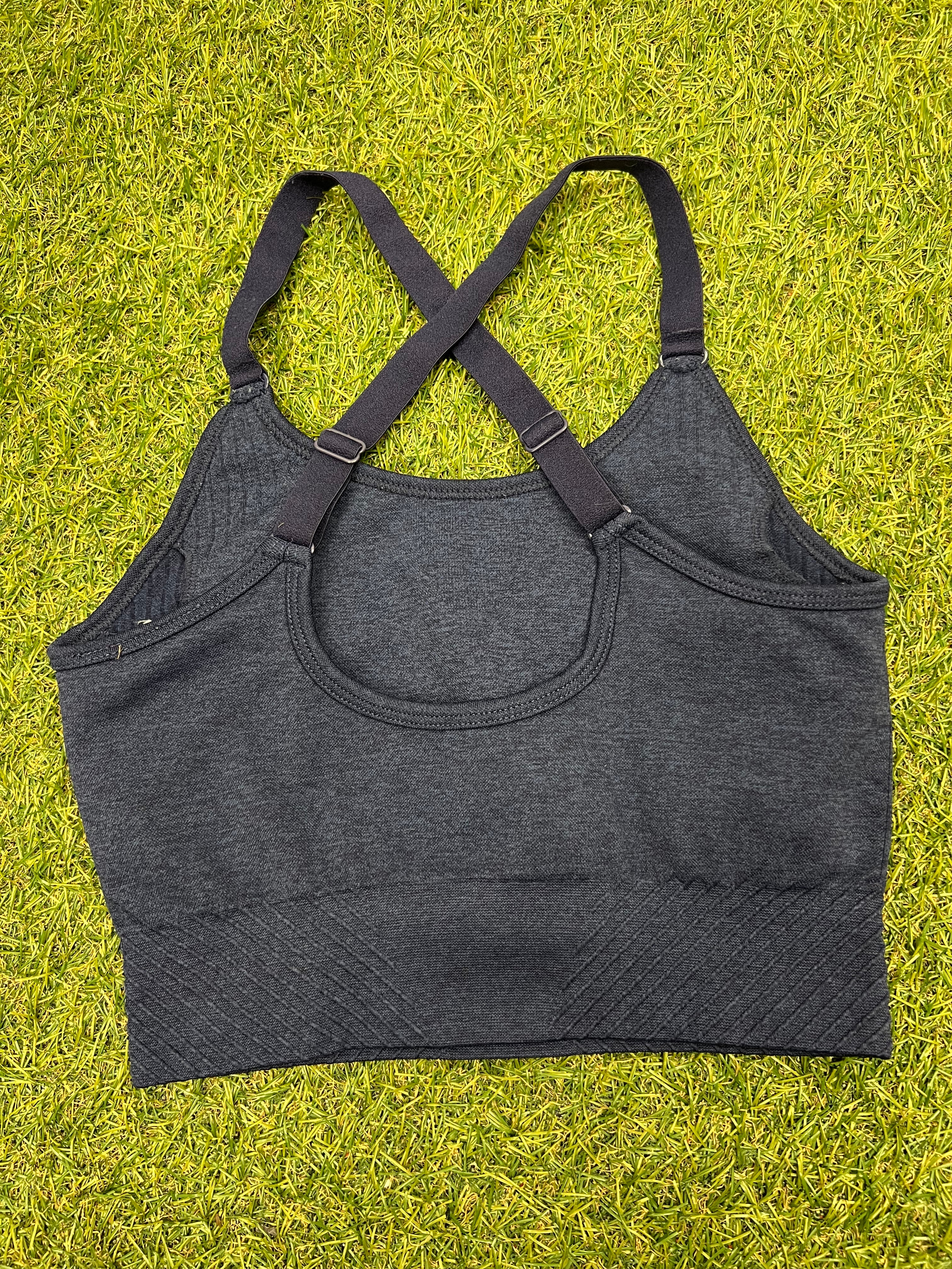 Back view of USA Pro navy marl sports bra top showing adjustable criss-cross straps on grass