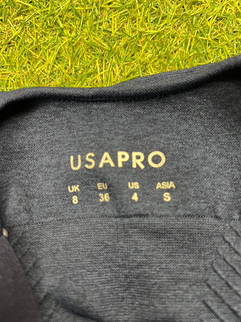 Close-up of size label inside USA Pro navy marl sports bra top indicating UK size 8