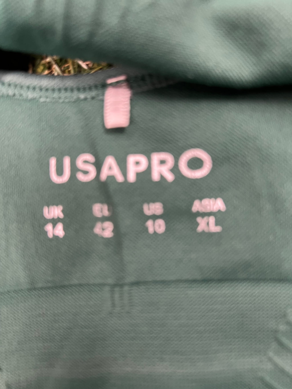 Close-up of USA Pro brand tag highlighting UK size 14 on the green sports bra