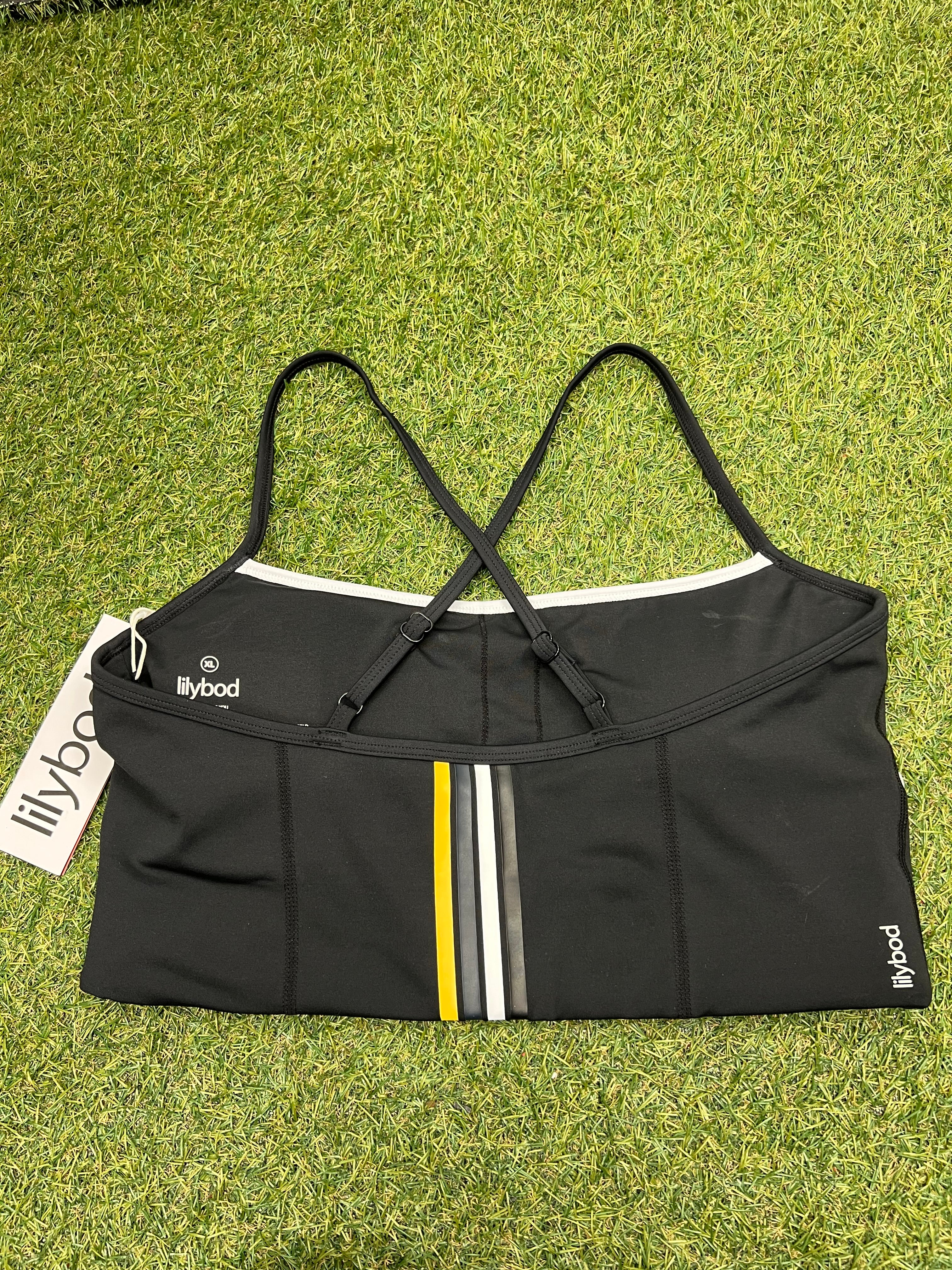 Lilybod black sports bra back view showing criss-cross adjustable straps and yellow-grey-white stripes