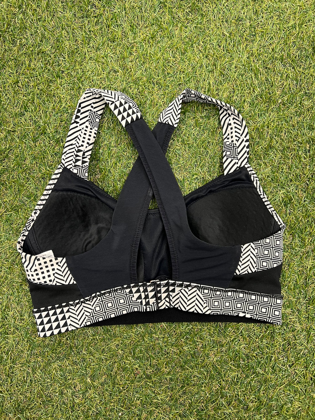 Back view of Brooks sports bra on grass showing criss-cross patterned straps and adjustable back hooks