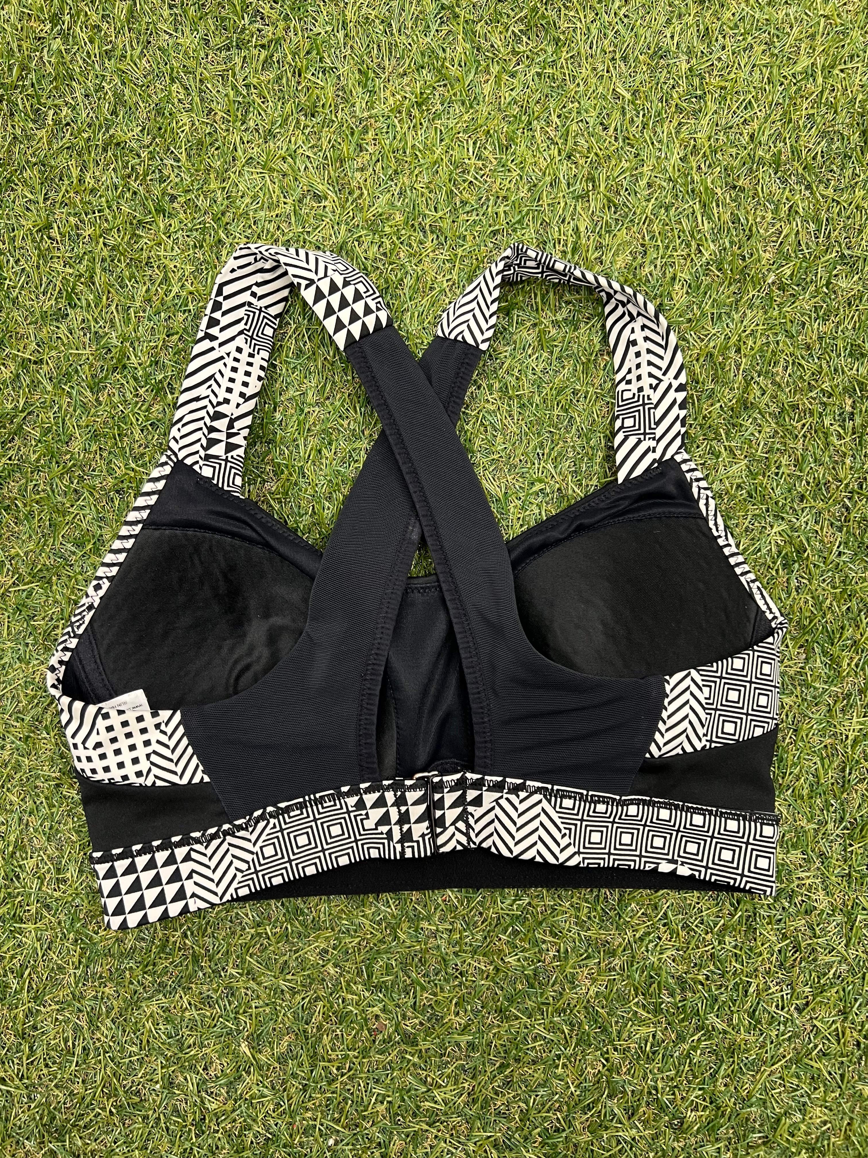 Back view of Brooks sports bra on grass showing criss-cross patterned straps and adjustable back hooks