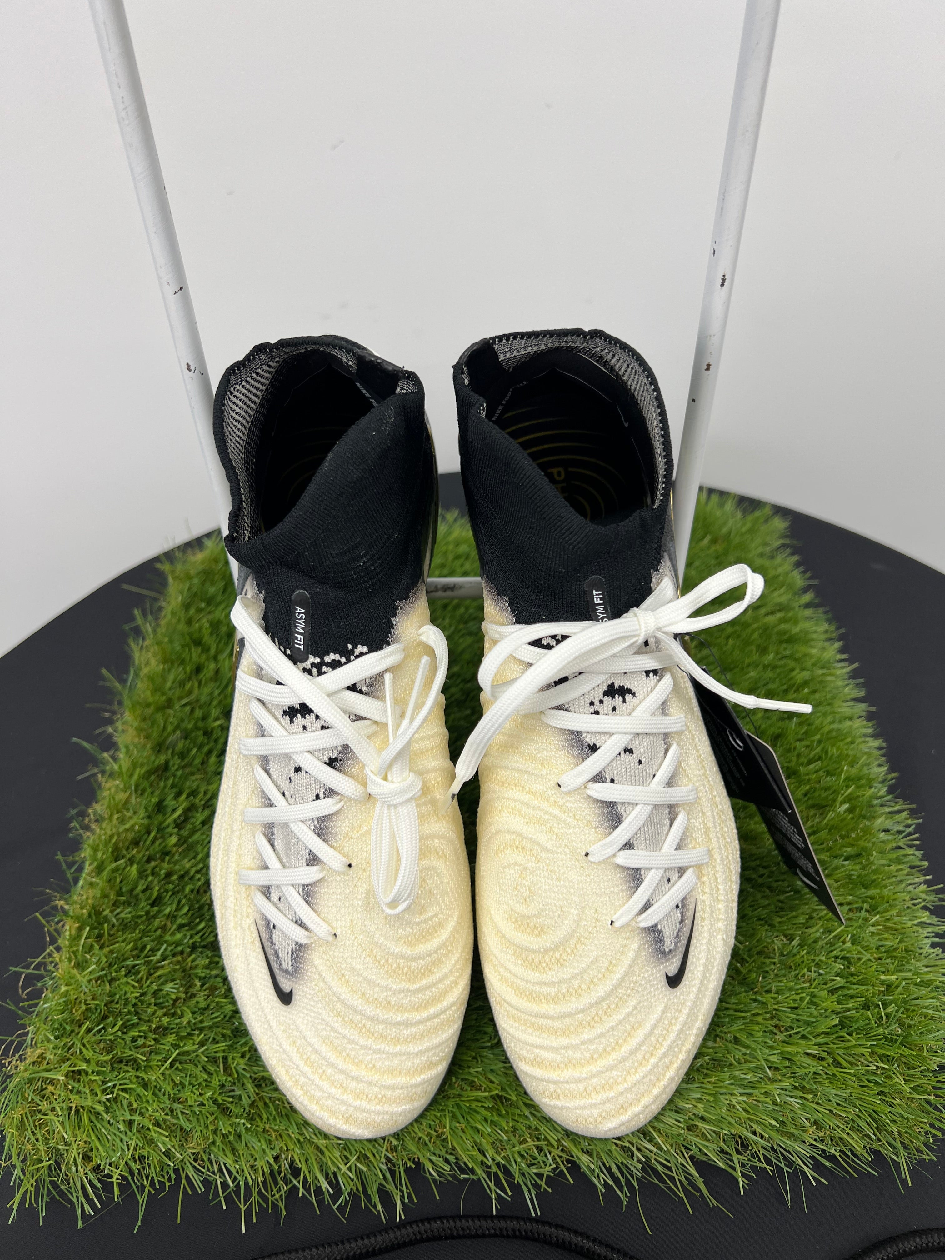 Top view of Nike Phantom Luna football boots in black and cream with white laces on artificial grass