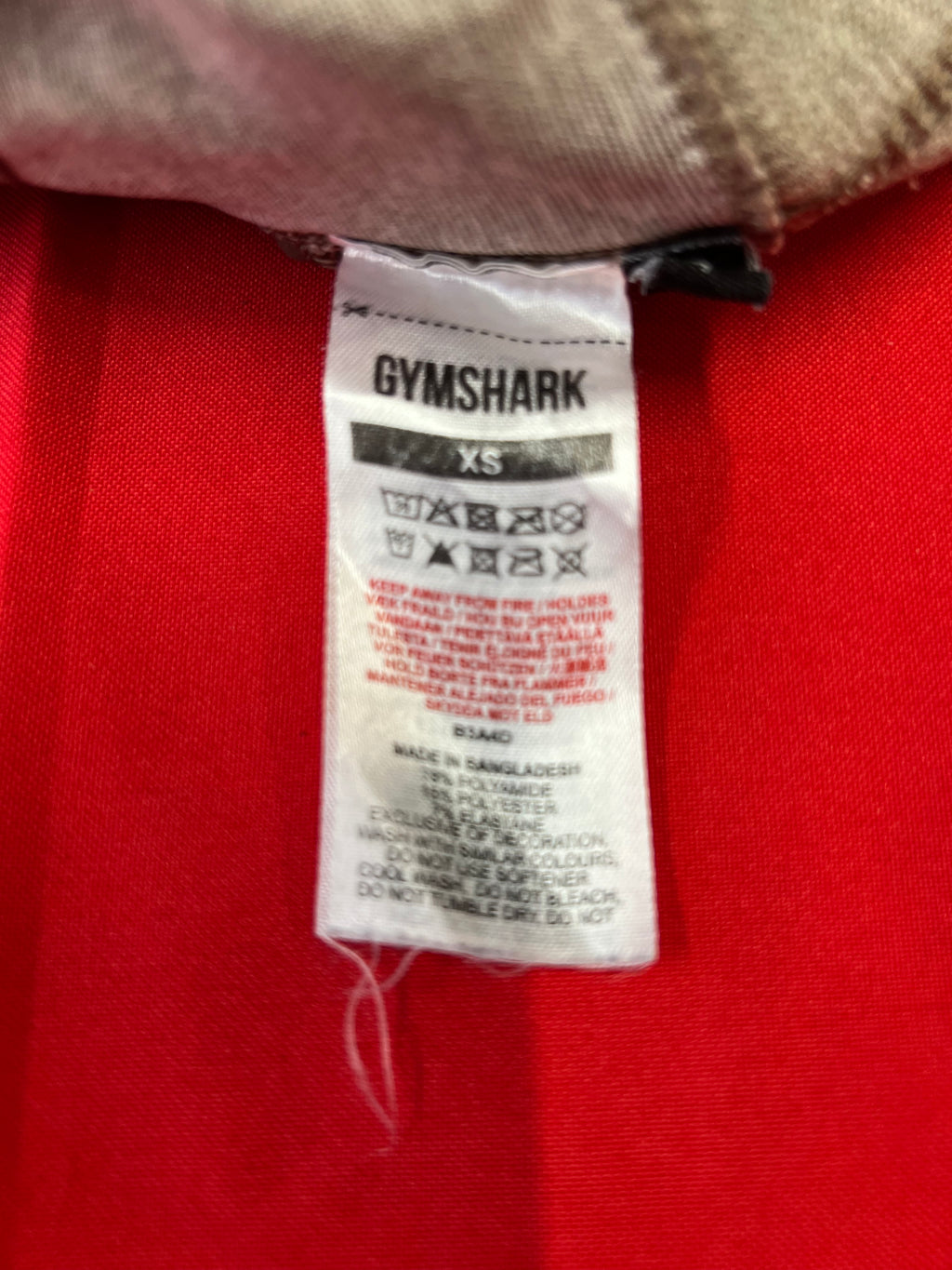 Close-up of Gymshark size XS care label showing fabric composition and washing instructions