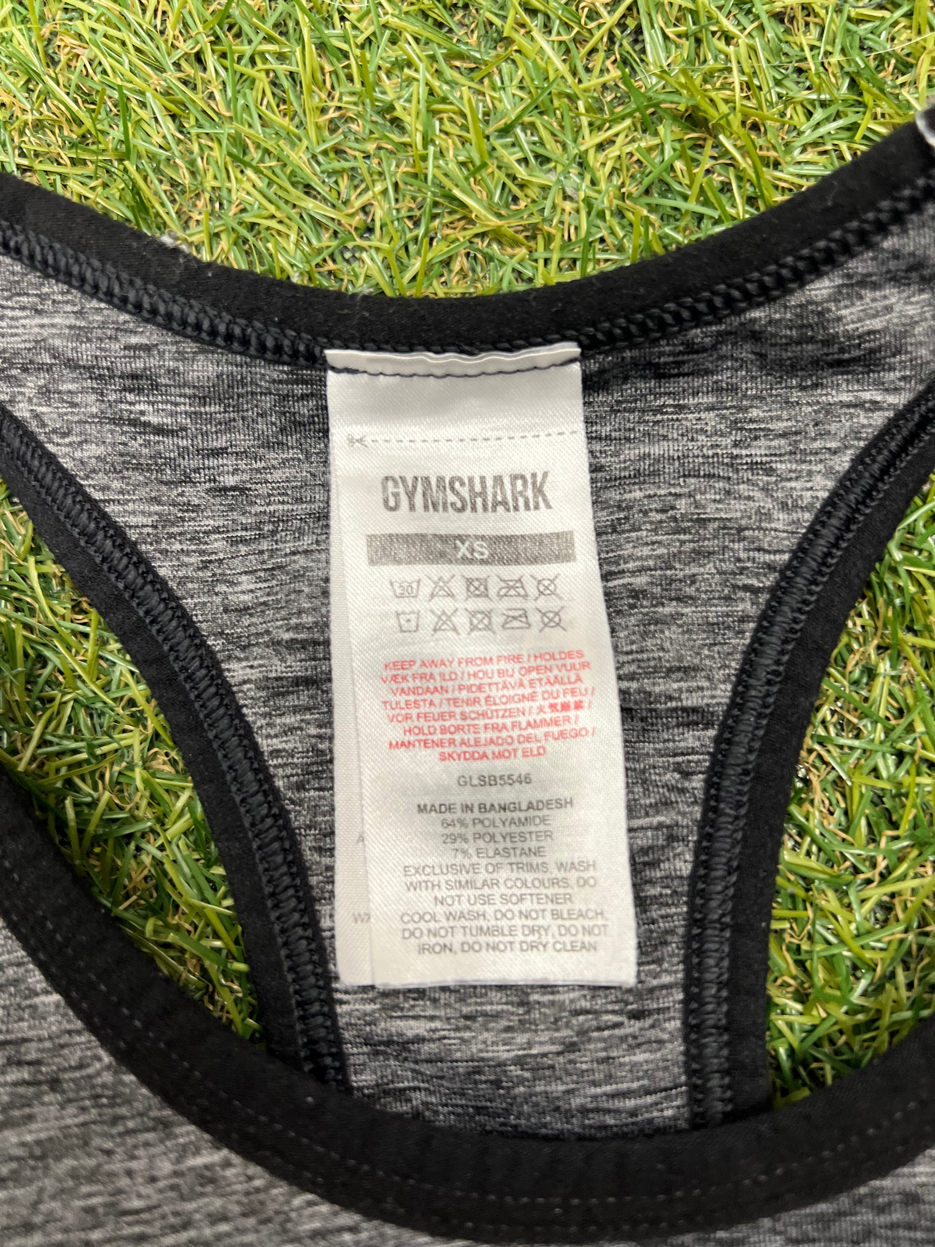Close-up of Gymshark XS size care label on grey and black sports bra
