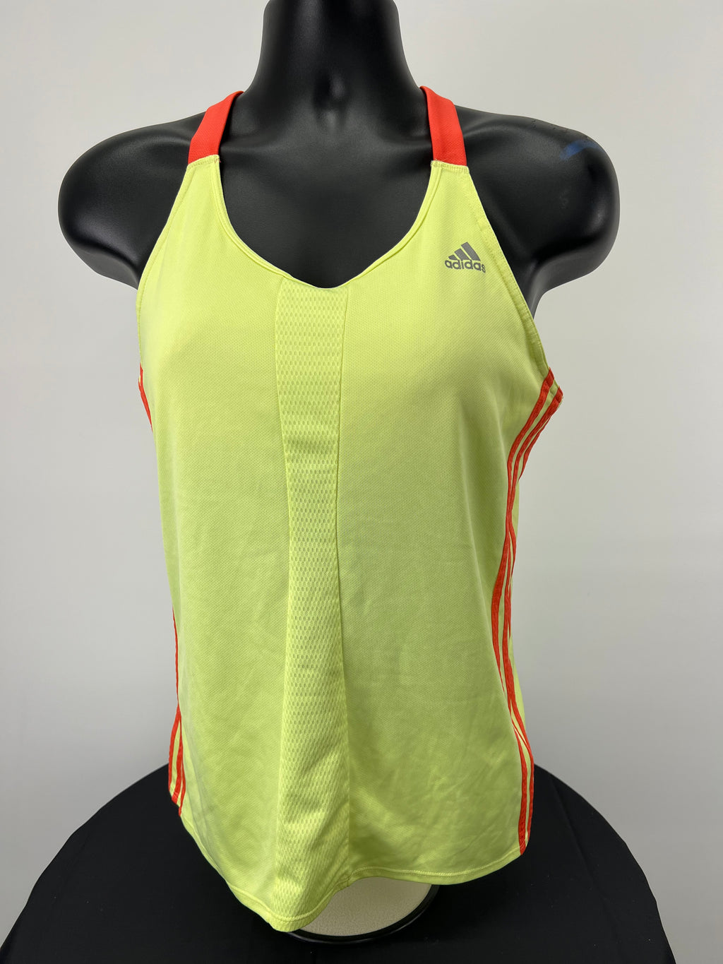 Front view of Adidas yellow Climalite sports vest with red straps on black mannequin