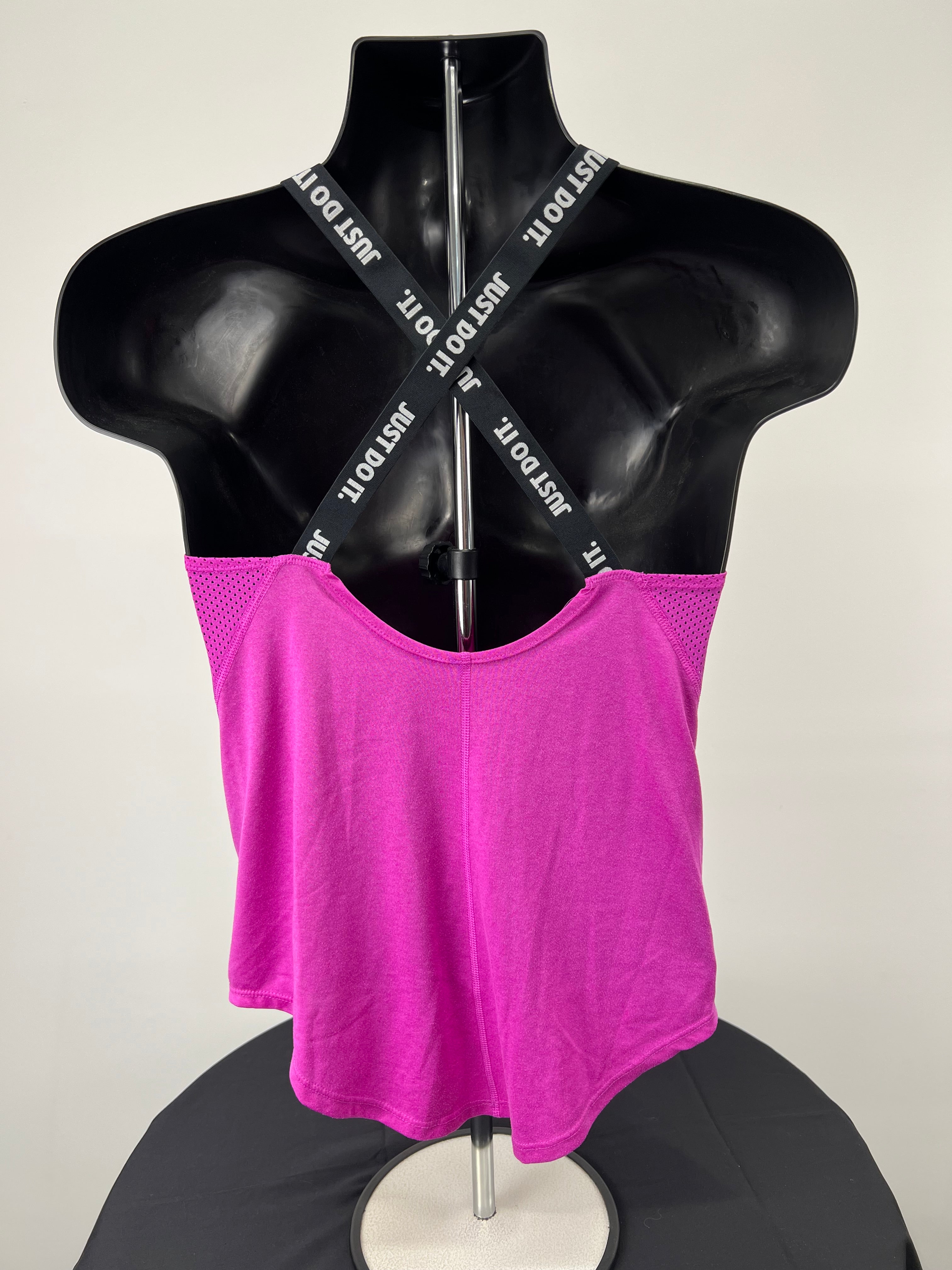 Back view of pink Nike sports vest showing crossed black straps with 'Just Do It.' branding on a mannequin