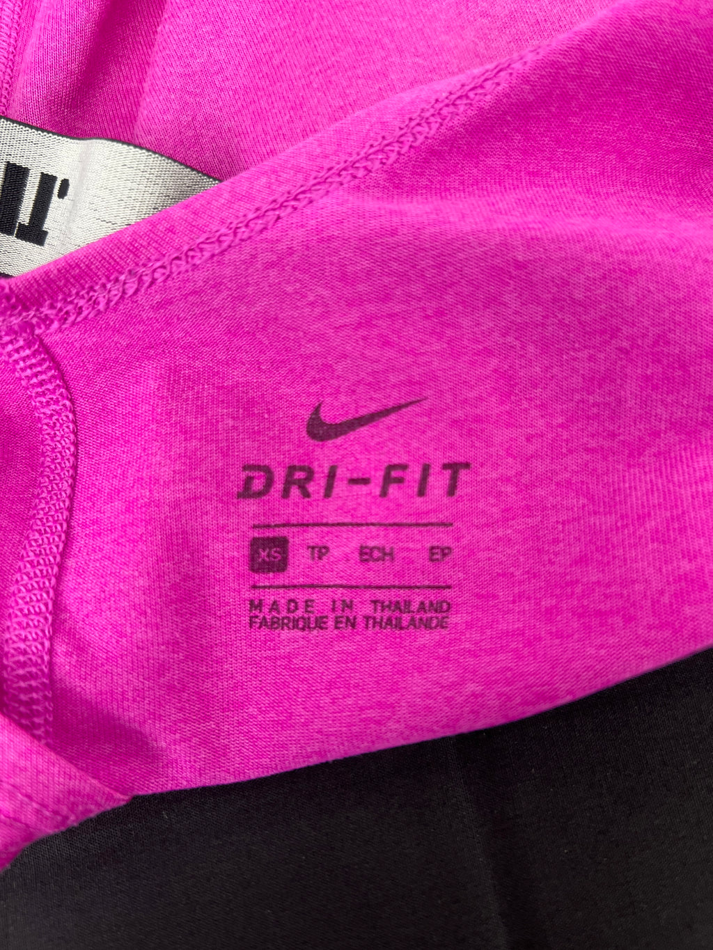Close-up of Nike Dri-FIT label printed on pink sports vest fabric
