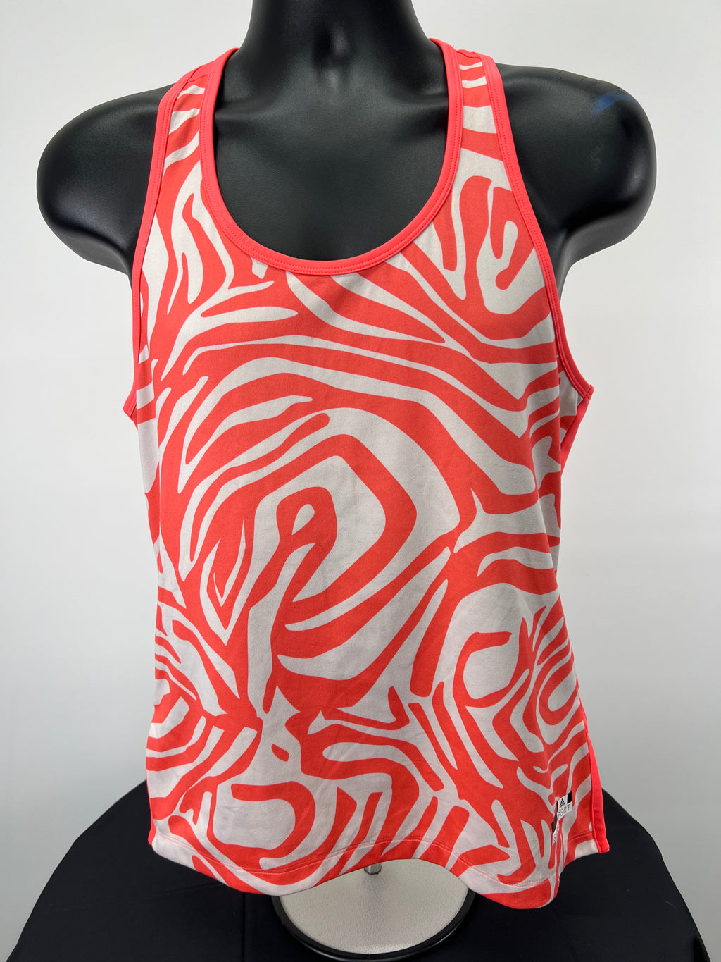 Front view of adidas Stella McCartney orange and white printed sports vest on black mannequin