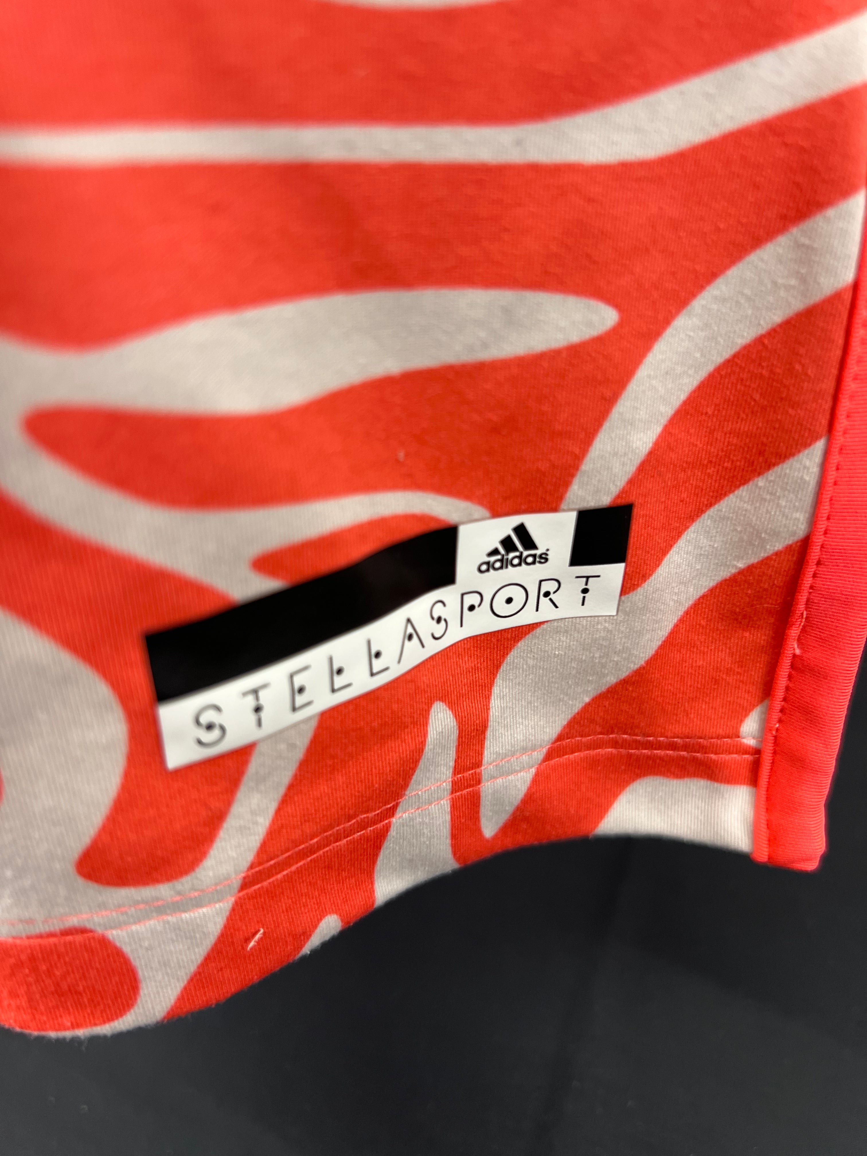 Close-up of adidas Stella McCartney Stellasport logo on bottom left of orange printed vest