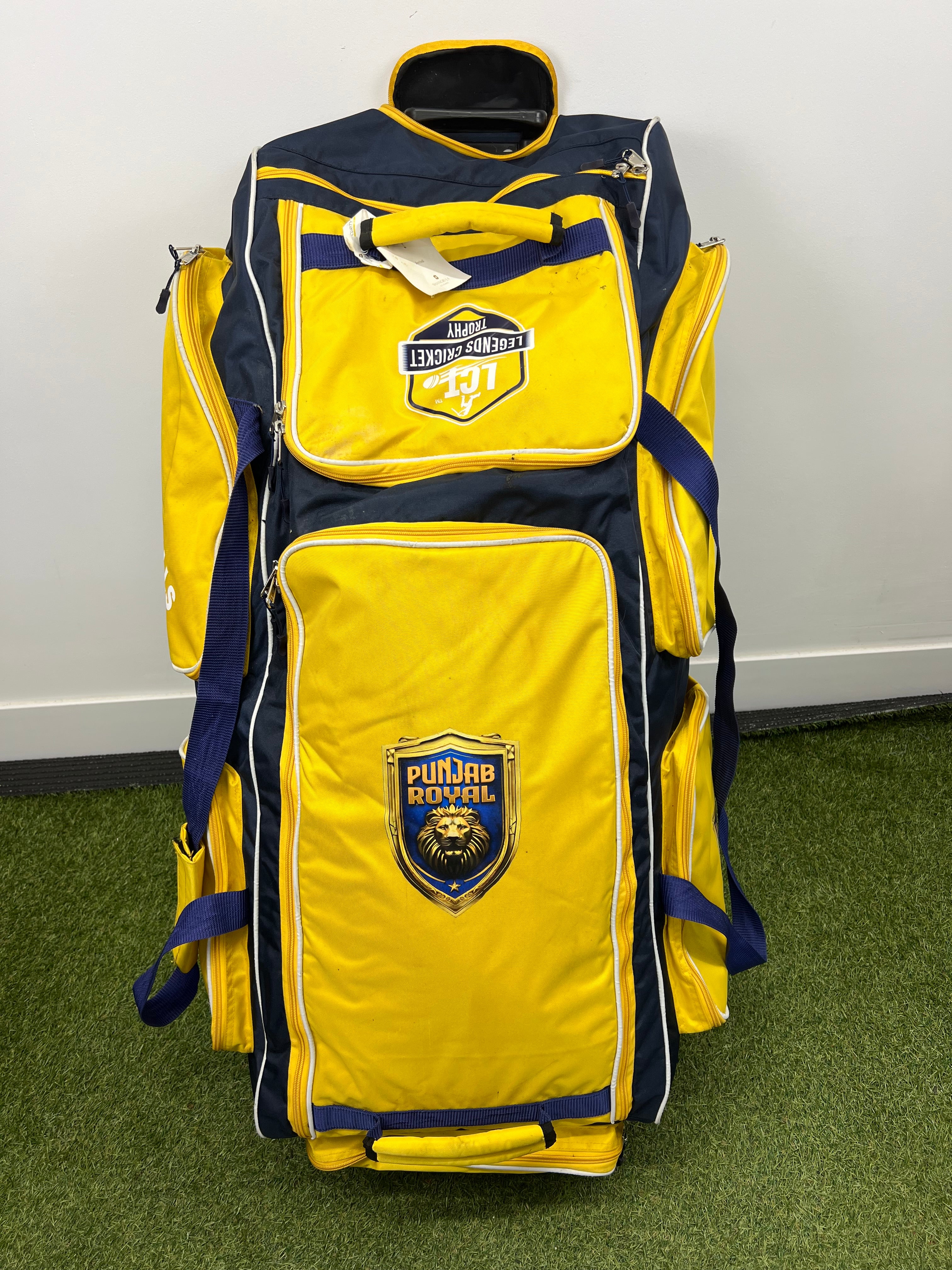 Front view of yellow and navy Punjab Royal wheeled cricket bag with multiple zip compartments and Punjab Royal logo