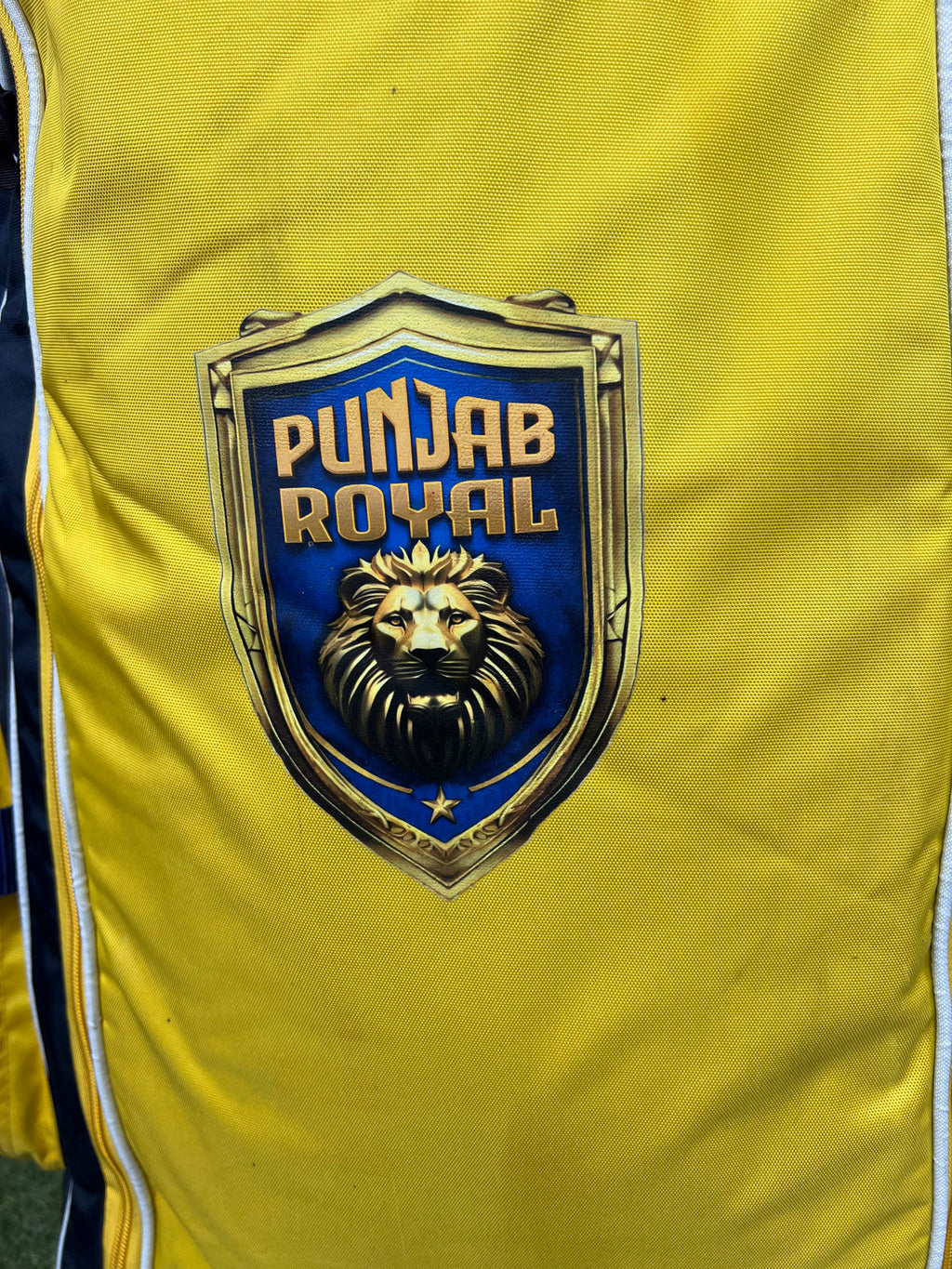 Close-up of Punjab Royal logo featuring a lion emblem on the yellow cricket bag