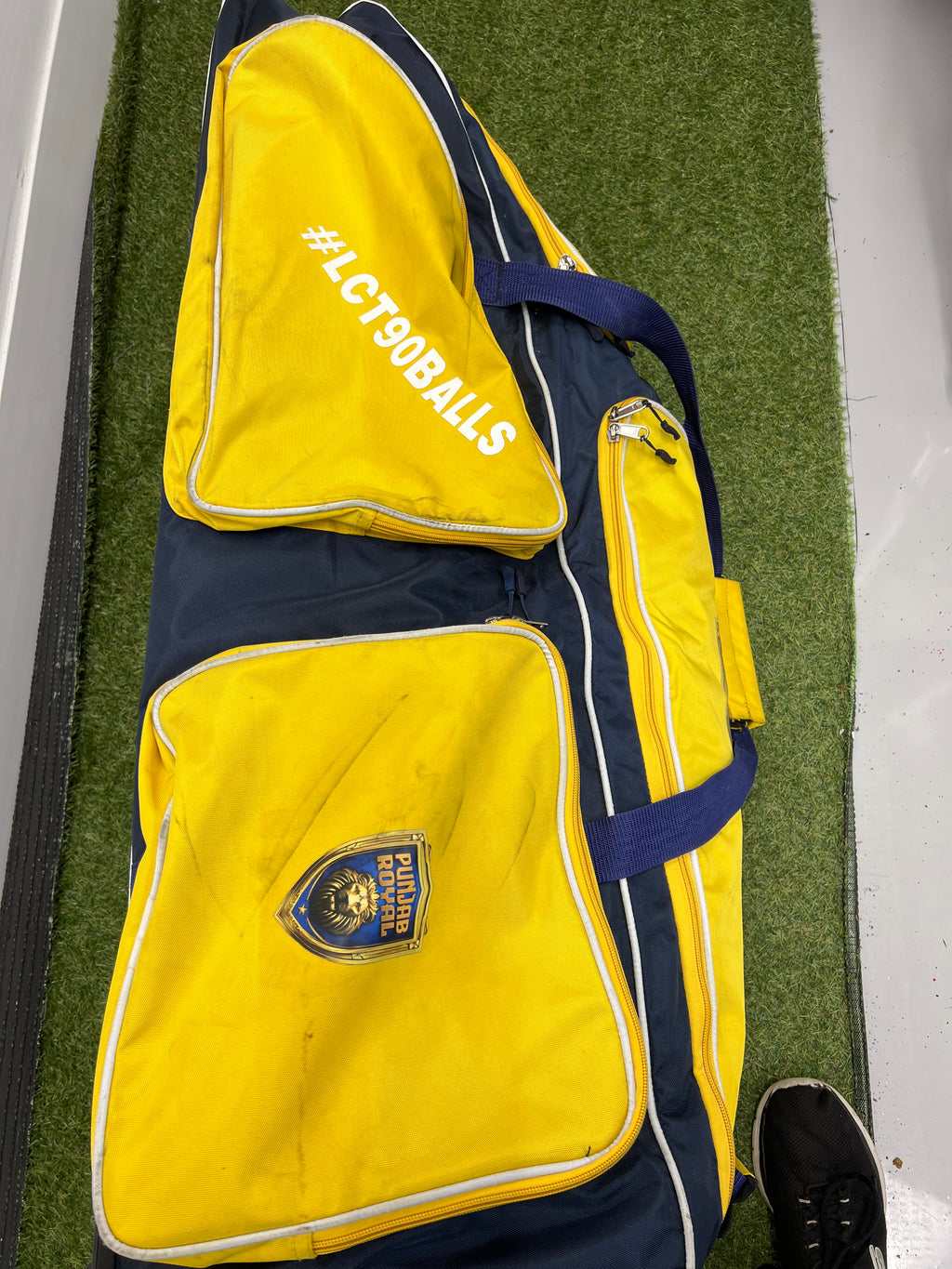 Side view of Punjab Royal cricket bag with #LCT90BALLS text on an outer pocket