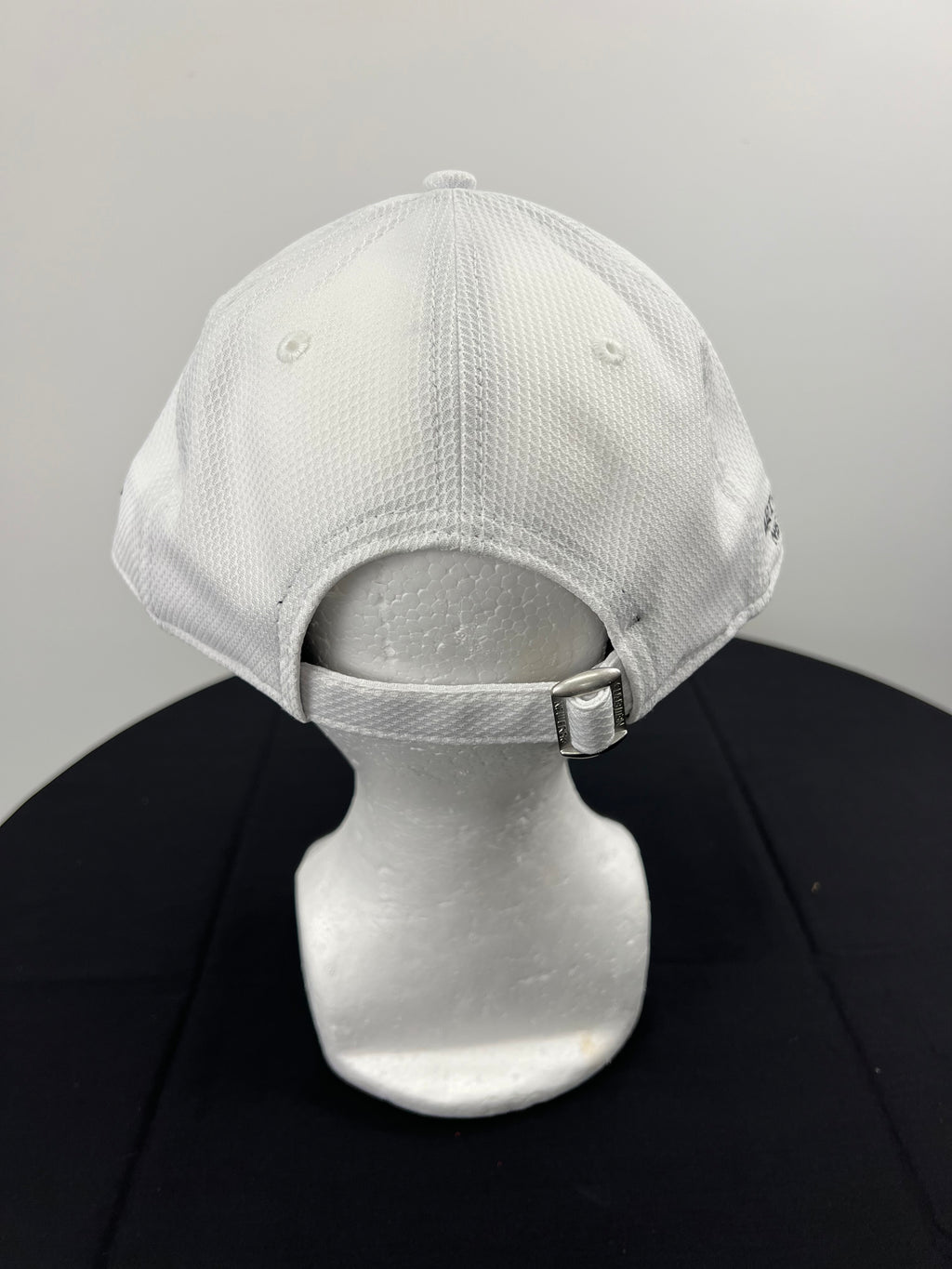 Back view of white cap with adjustable strap and metal clasp