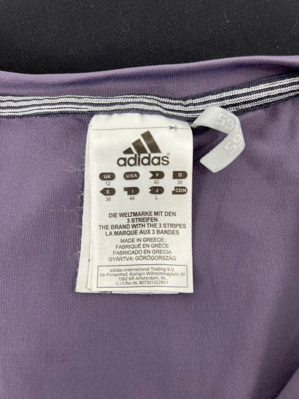 Close-up of adidas size and care label inside mauve sleeveless vest top