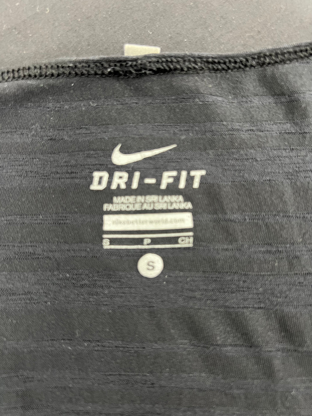 Close-up of Nike Dri-FIT logo and size label inside black sports vest