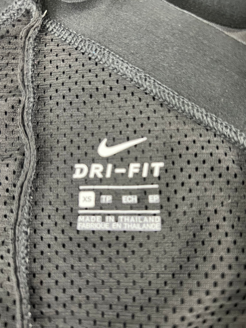 Close-up of inside label of Nike vest showing Dri-Fit technology and size XS