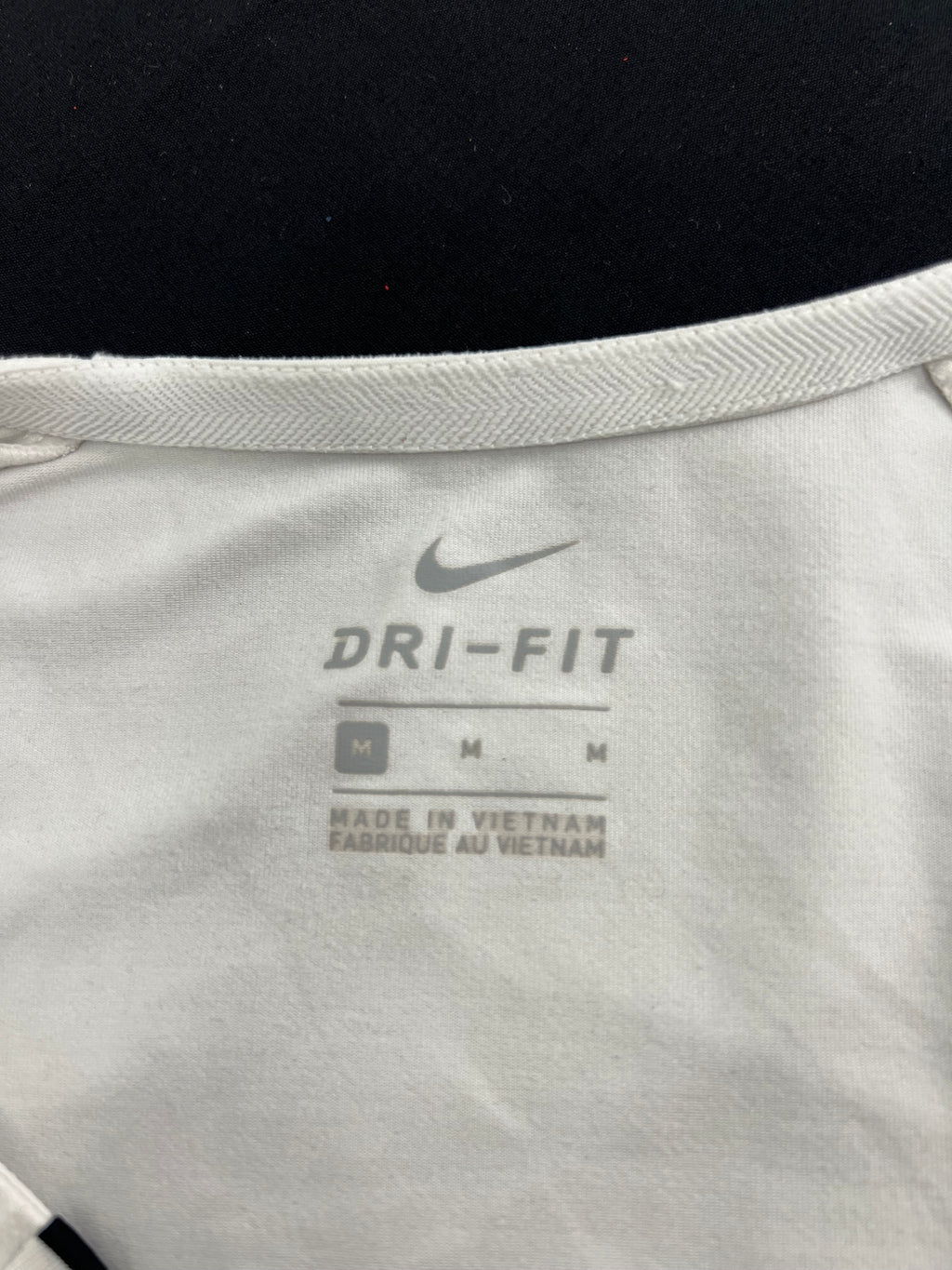 Close-up of inside neck label showing Nike Dri-Fit logo and size Medium